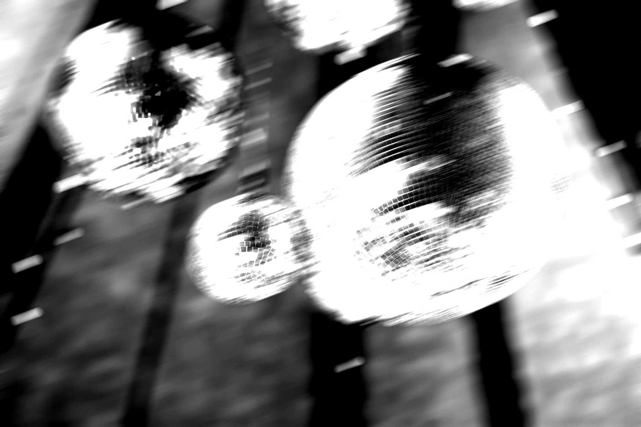 Multiple disco balls hanging from the ceiling with reflections and light patterns.
