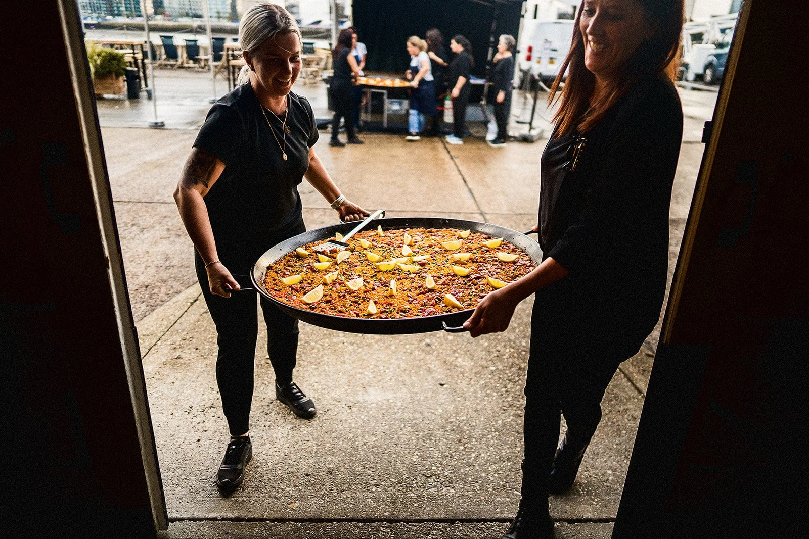 Waiters carrying a giant paella into a cool London warehouse event