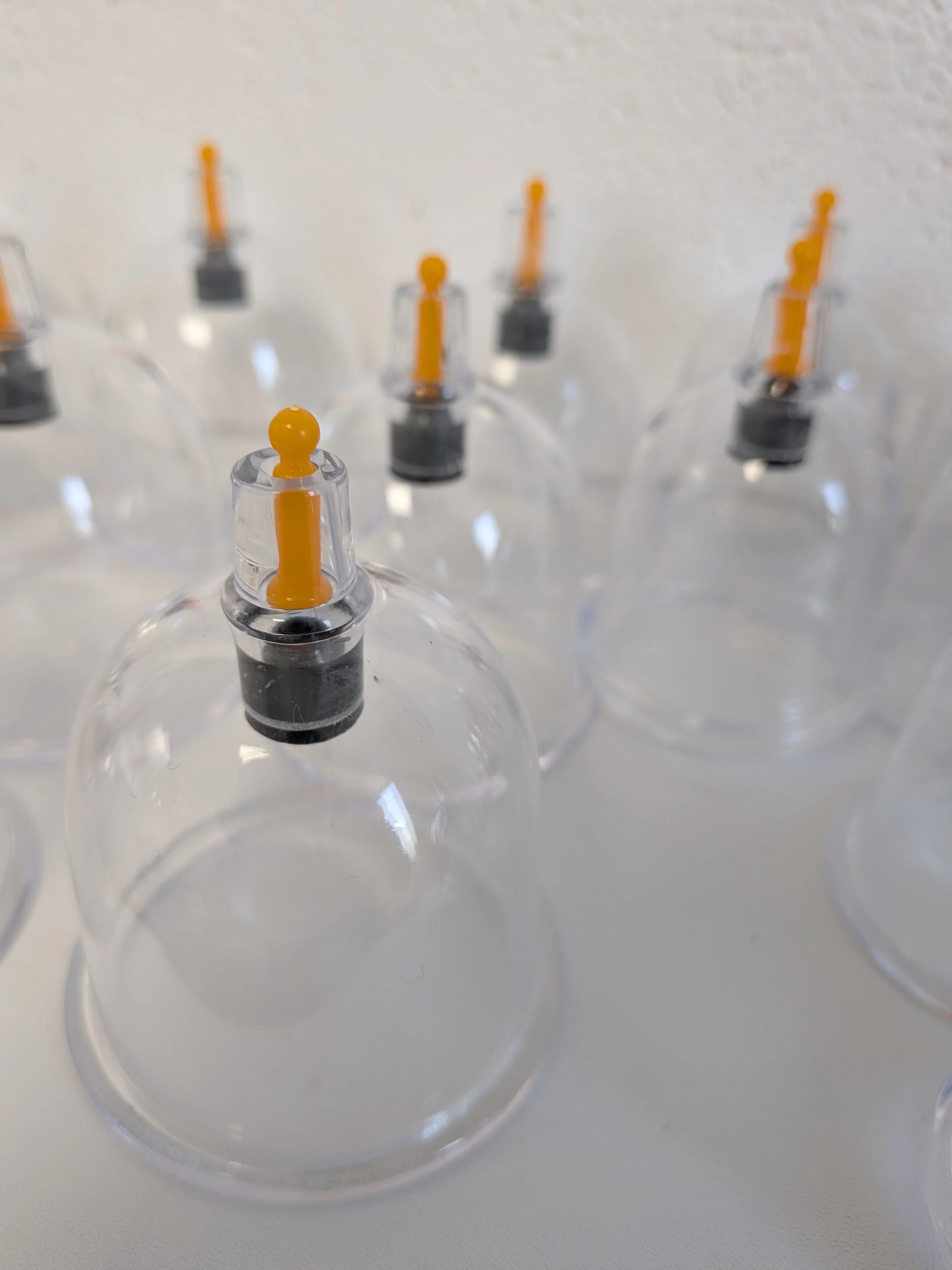 Multiple empty clear glass bottles with orange droppers on top, arranged on a white surface.