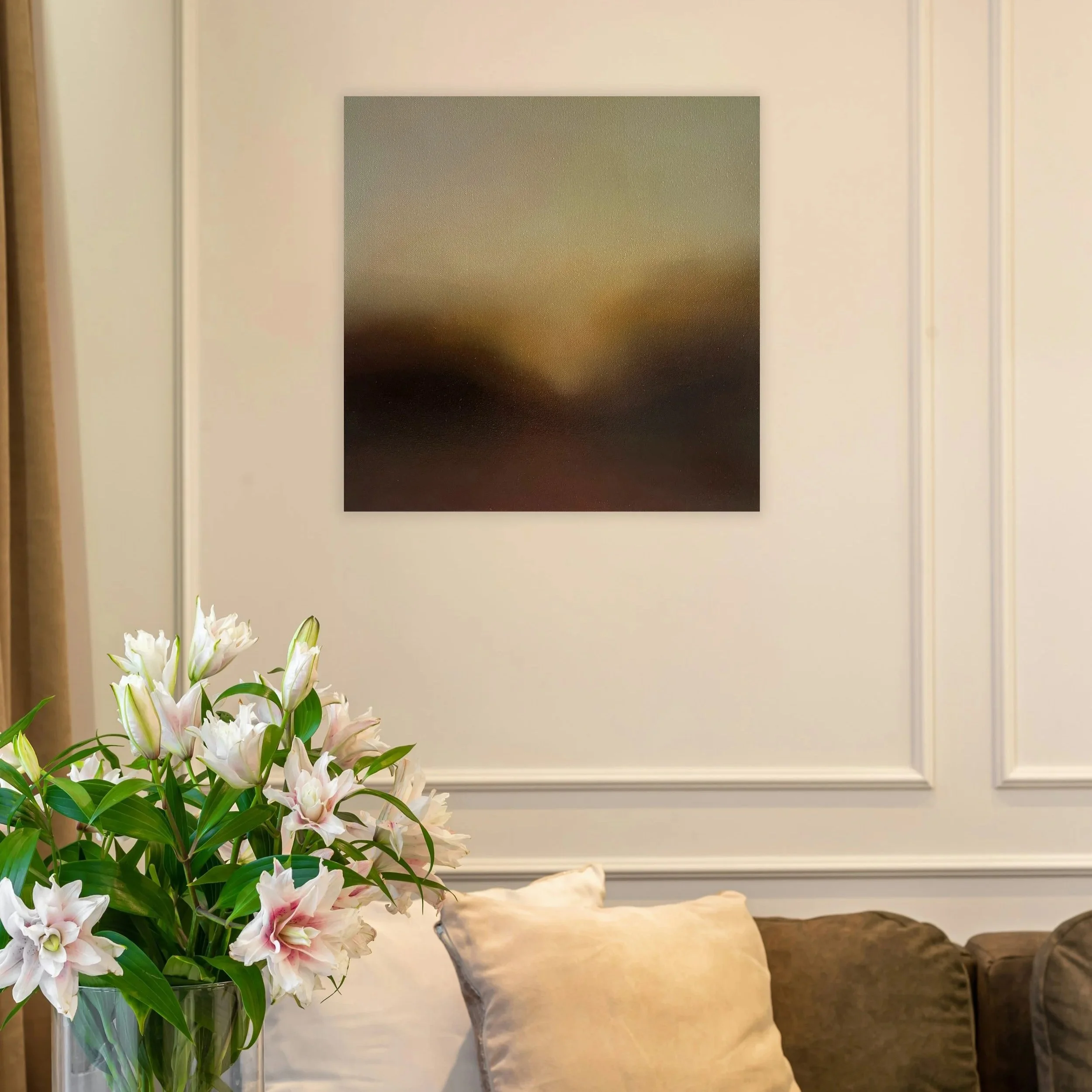 Un bouquet de fleurs blanches et roses dans un vase en verre, placé sur une table, avec un mur beige en fond et un tableau noir accroché au mur.