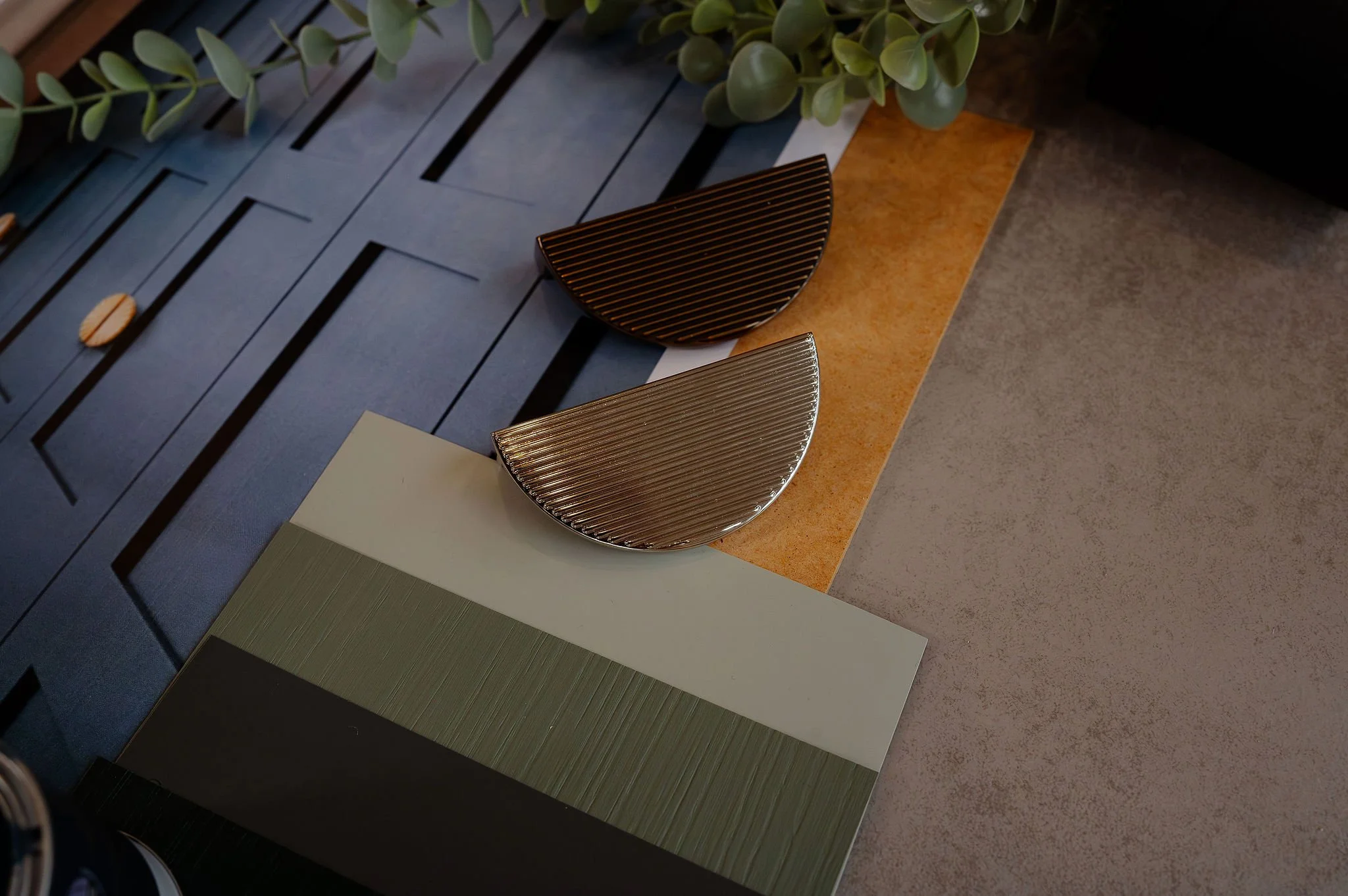 Decorative semicircular objects on a surface with textured panels, foliage, and various materials.