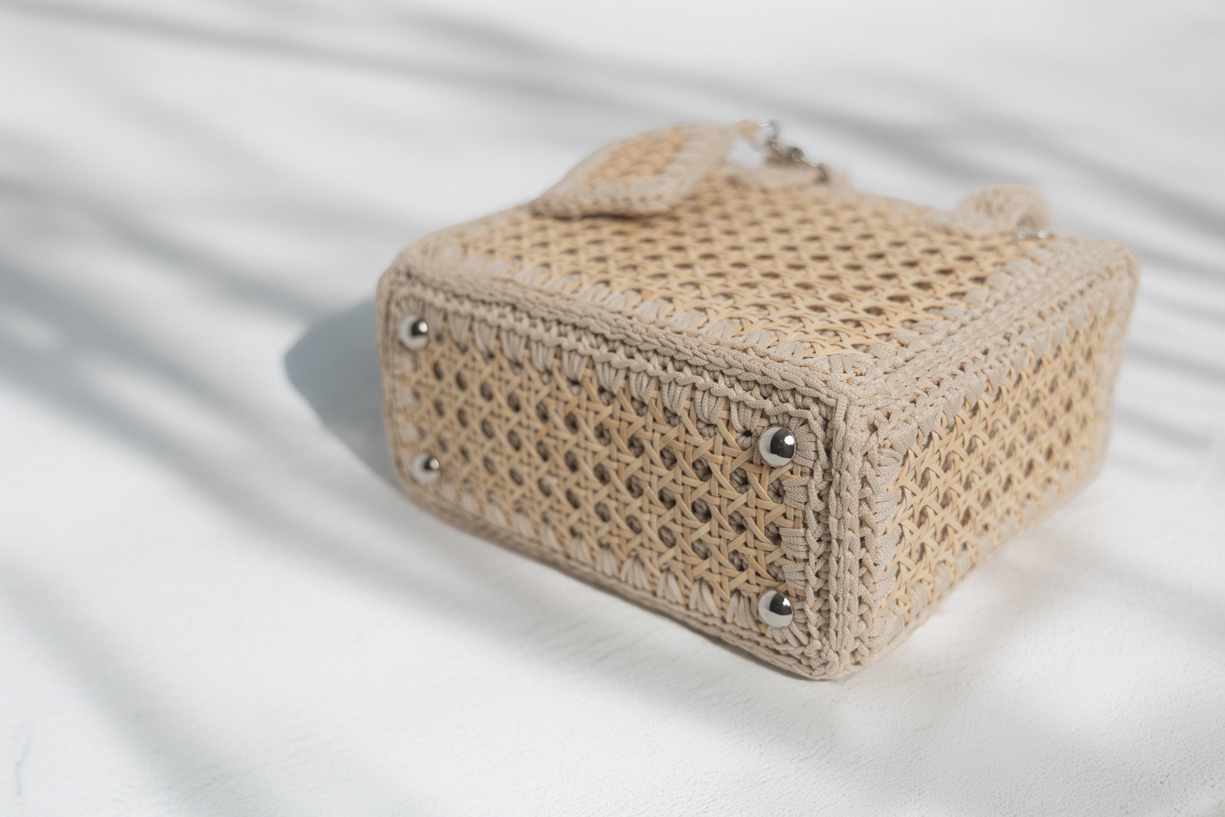 Rectangular woven straw handbag on white surface with shadows.