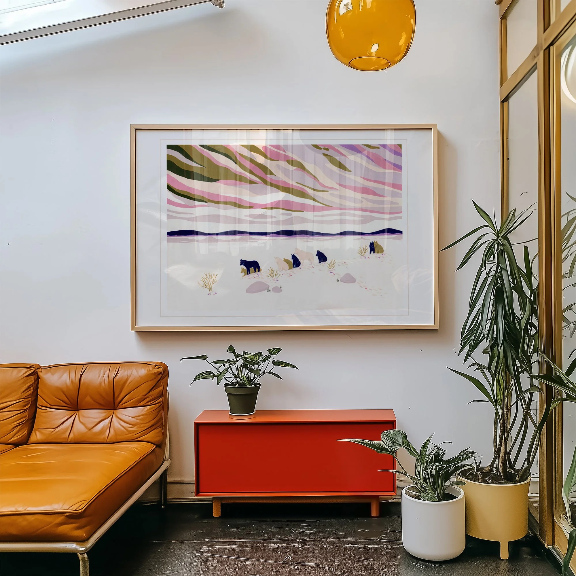 Modern living room with a framed art piece of a winter landscape with five bears, a brown leather sofa, a red side table with a potted plant, and two larger potted plants on the floor.