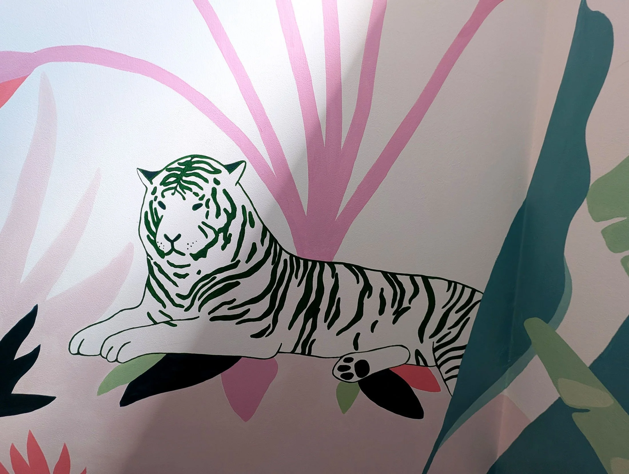 Wall mural of a tiger with green stripes lying among abstract pink and green foliage