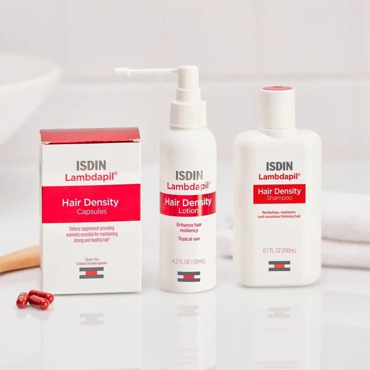 ISDIN Lambdapil Hair Density products including capsules, lotion, and shampoo on a counter with a towel.