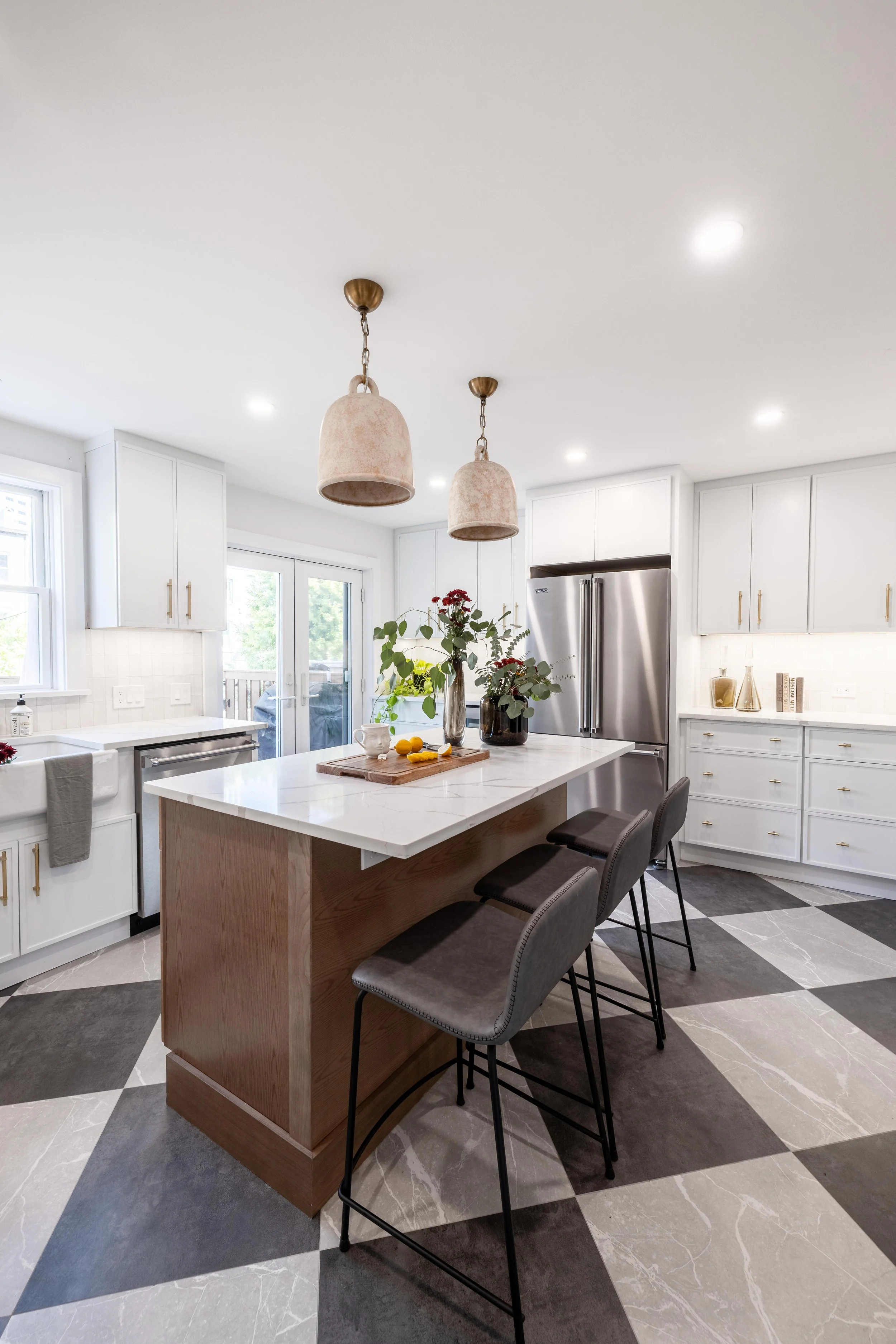 Modern kitchen with a large island, pendant lights, built-in appliances, and checkered flooring.