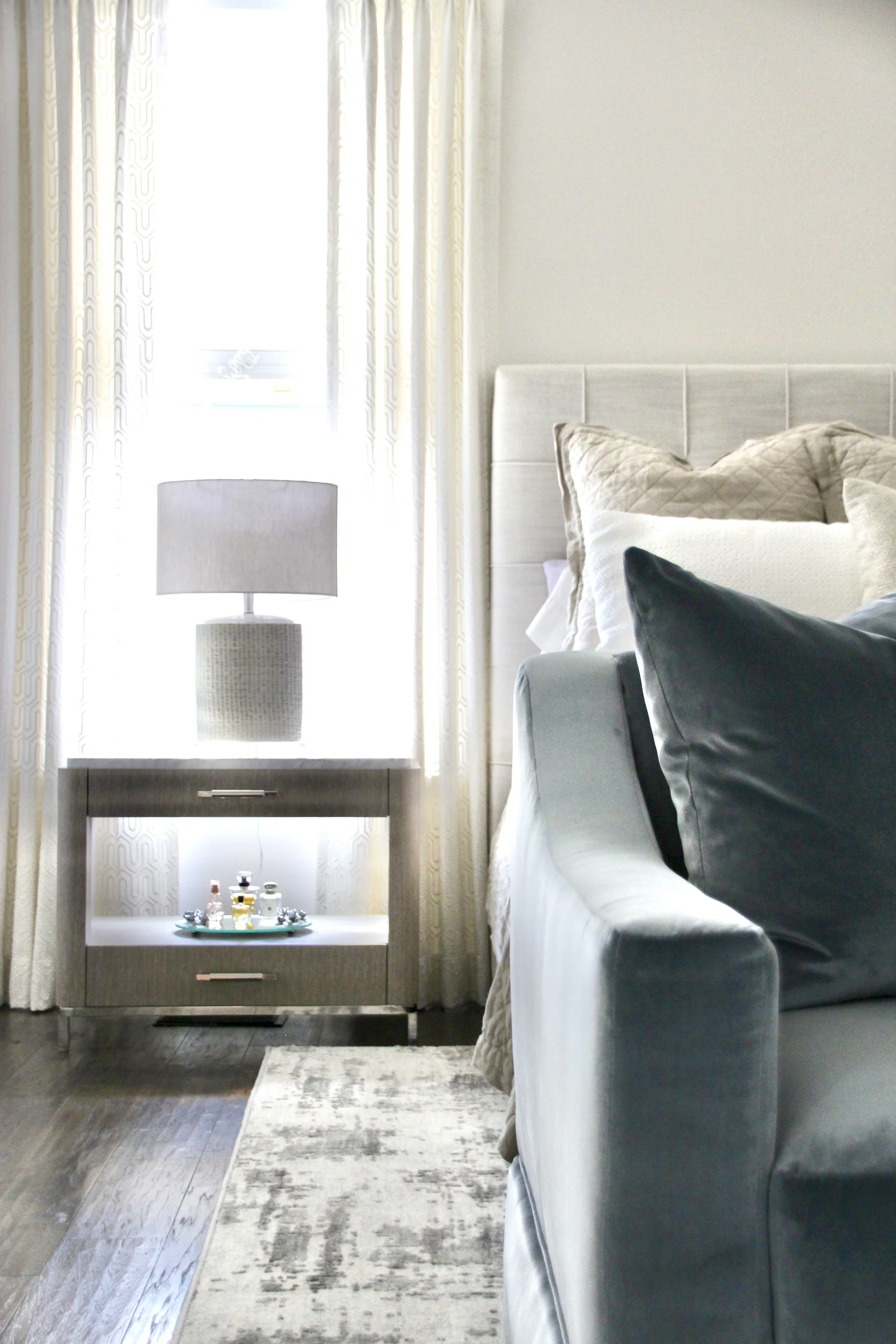 Modern bedroom interior with bed, pillows, nightstand, and lamp.