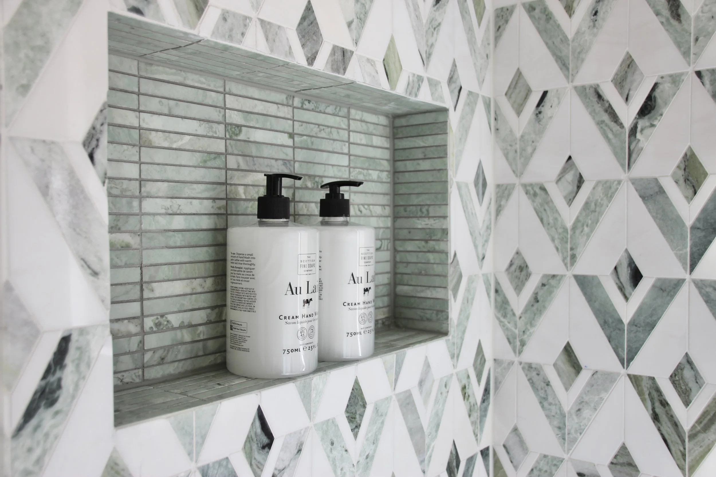 Bathroom shelf with marble tiles, bottles of cream hand wash