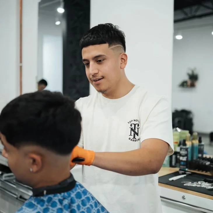 Barber cutting a customer's hair in a modern salon.