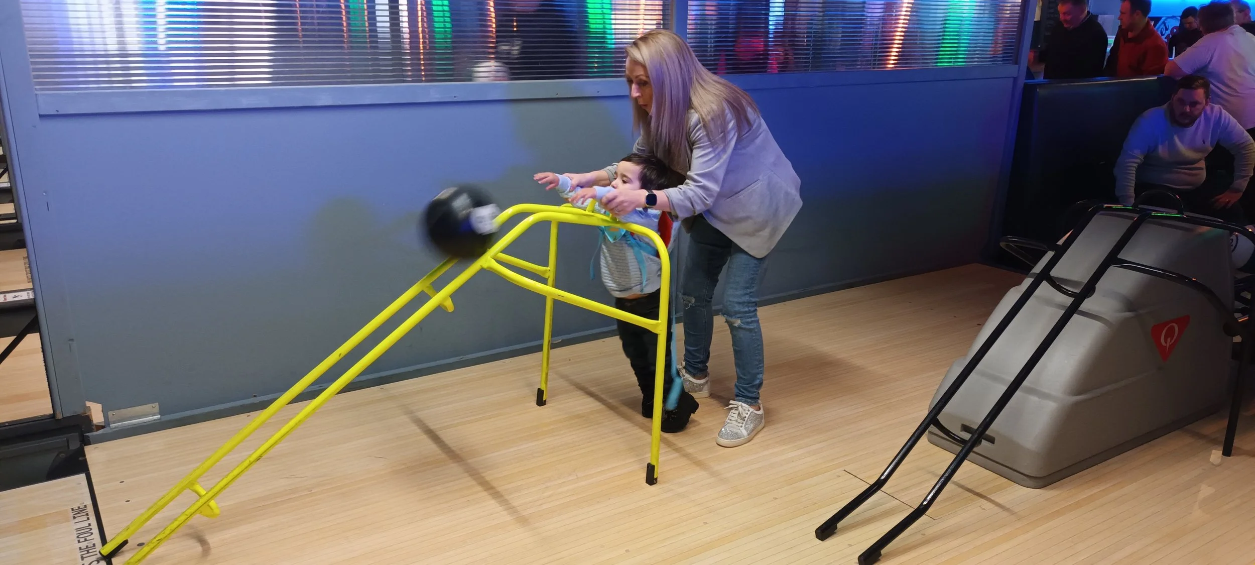 young child rolling bowling ball