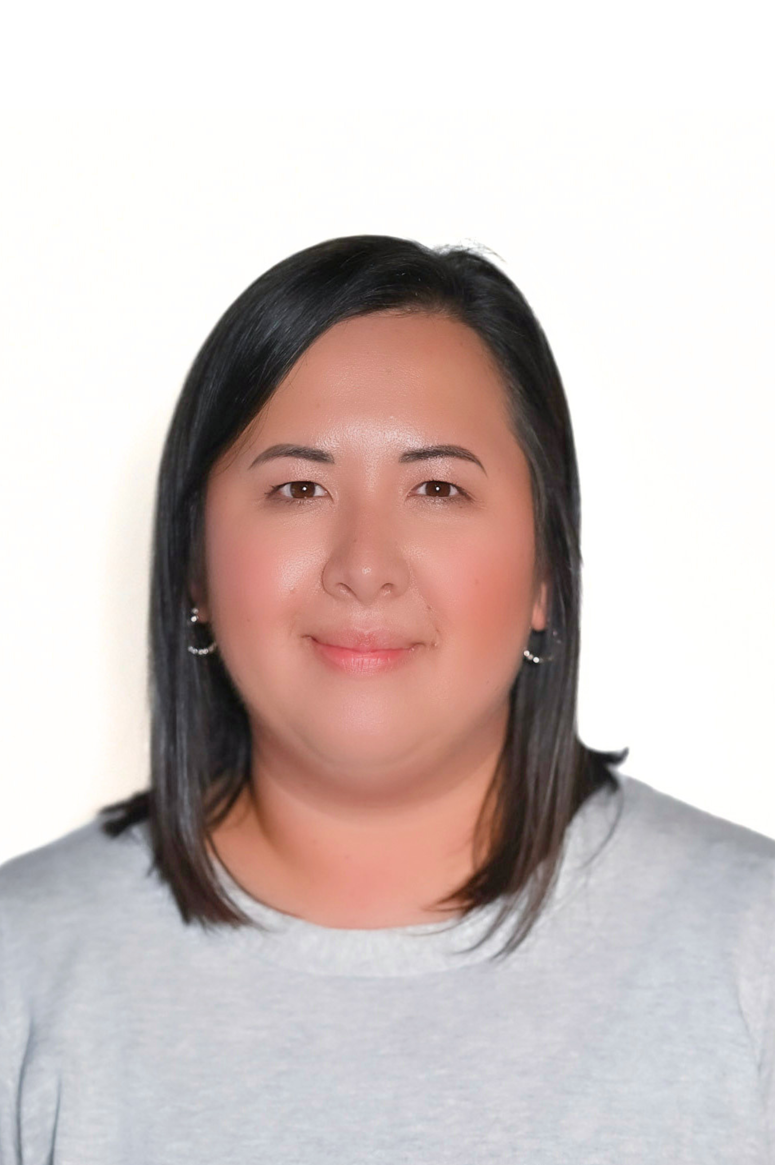 Portrait of a person with medium-length dark hair wearing a light gray sweater, against a plain background.