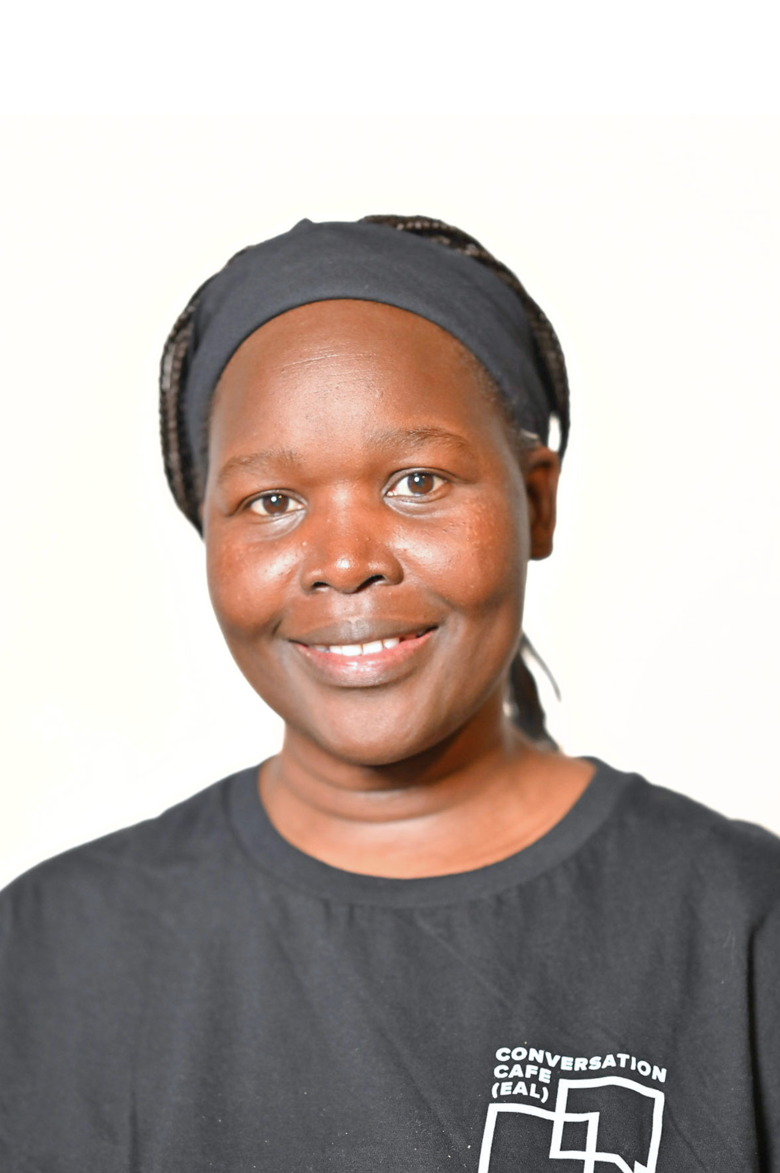 Person smiling, wearing a black shirt with "Conversation Cafe (EAL)" logo.