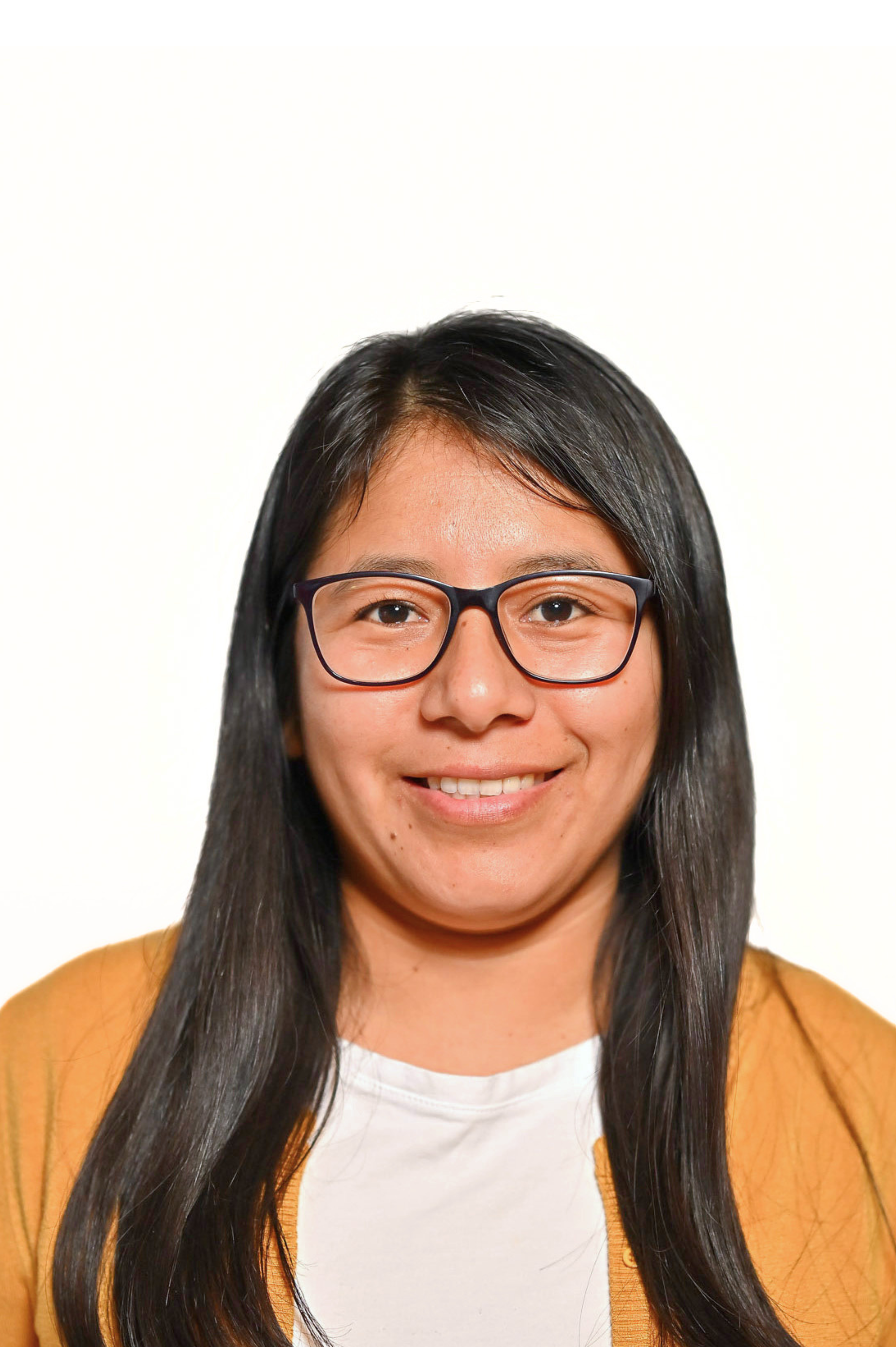 Person with long black hair, wearing glasses and a yellow cardigan, smiling against a plain background.