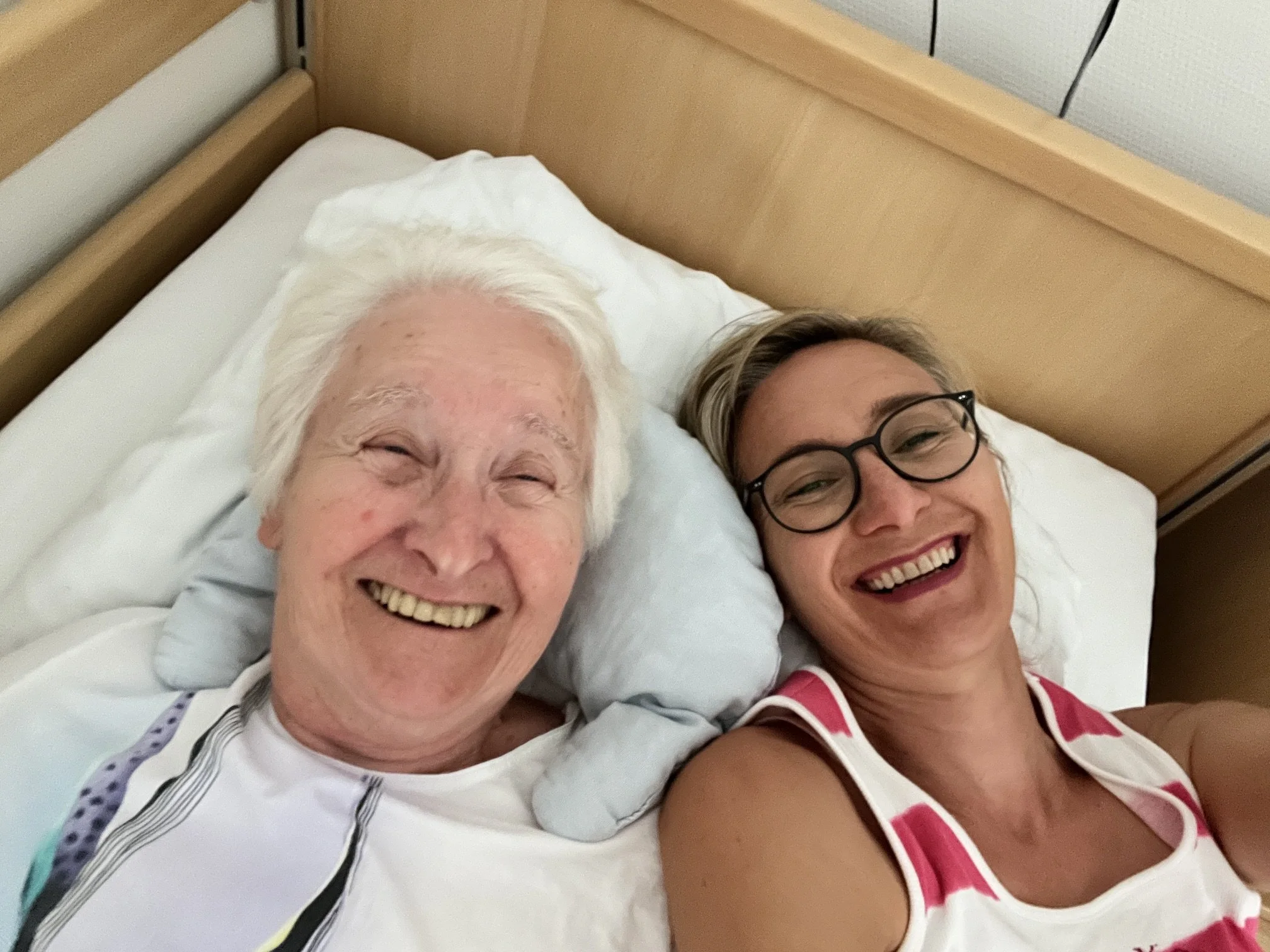 Zwei lachende Menschen im Bett liegend.