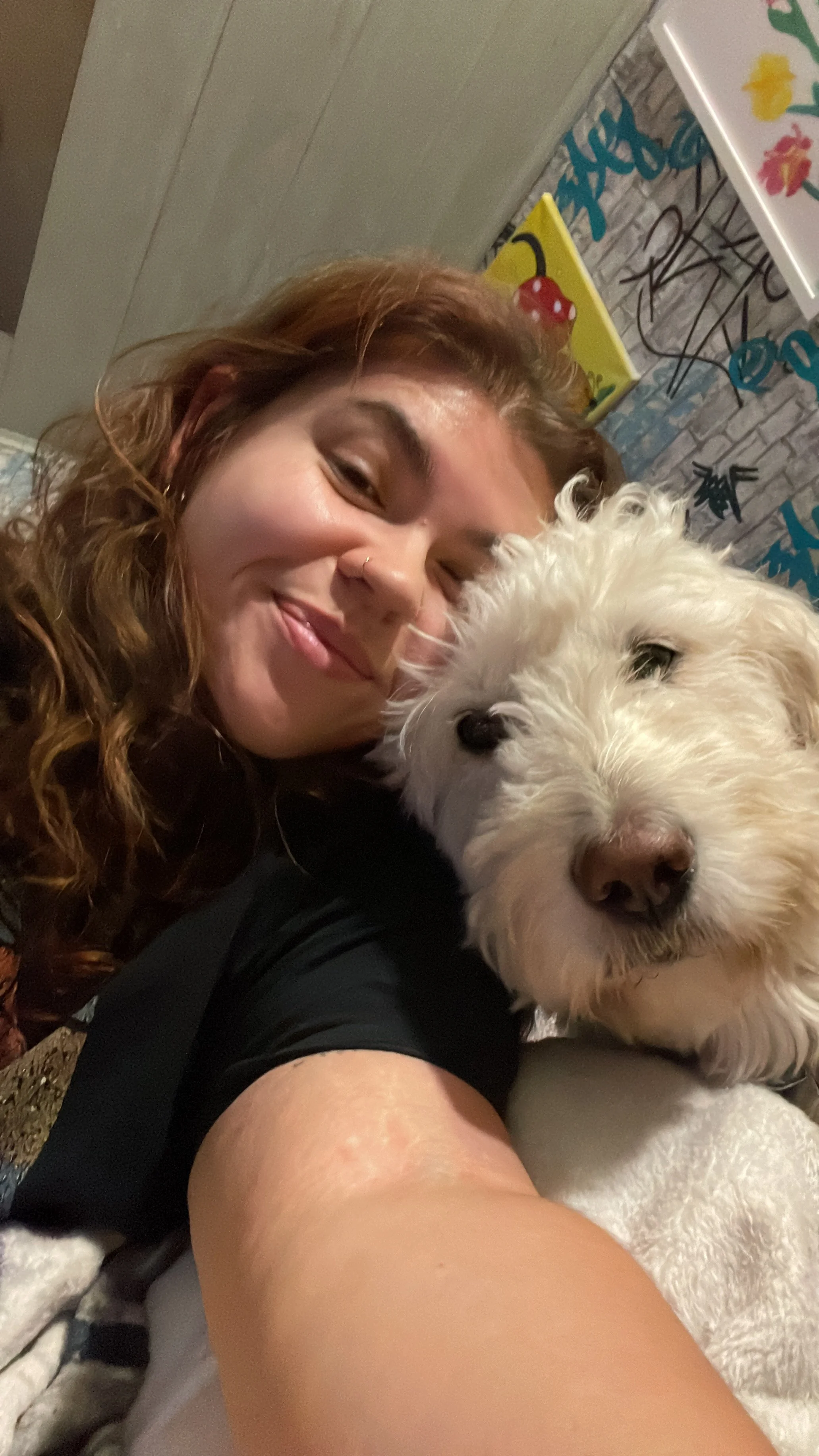 Frau lächelt in die Kamera und hält einen weißen Hund liebevoll im Arm – emotionales Haustier-Selfie