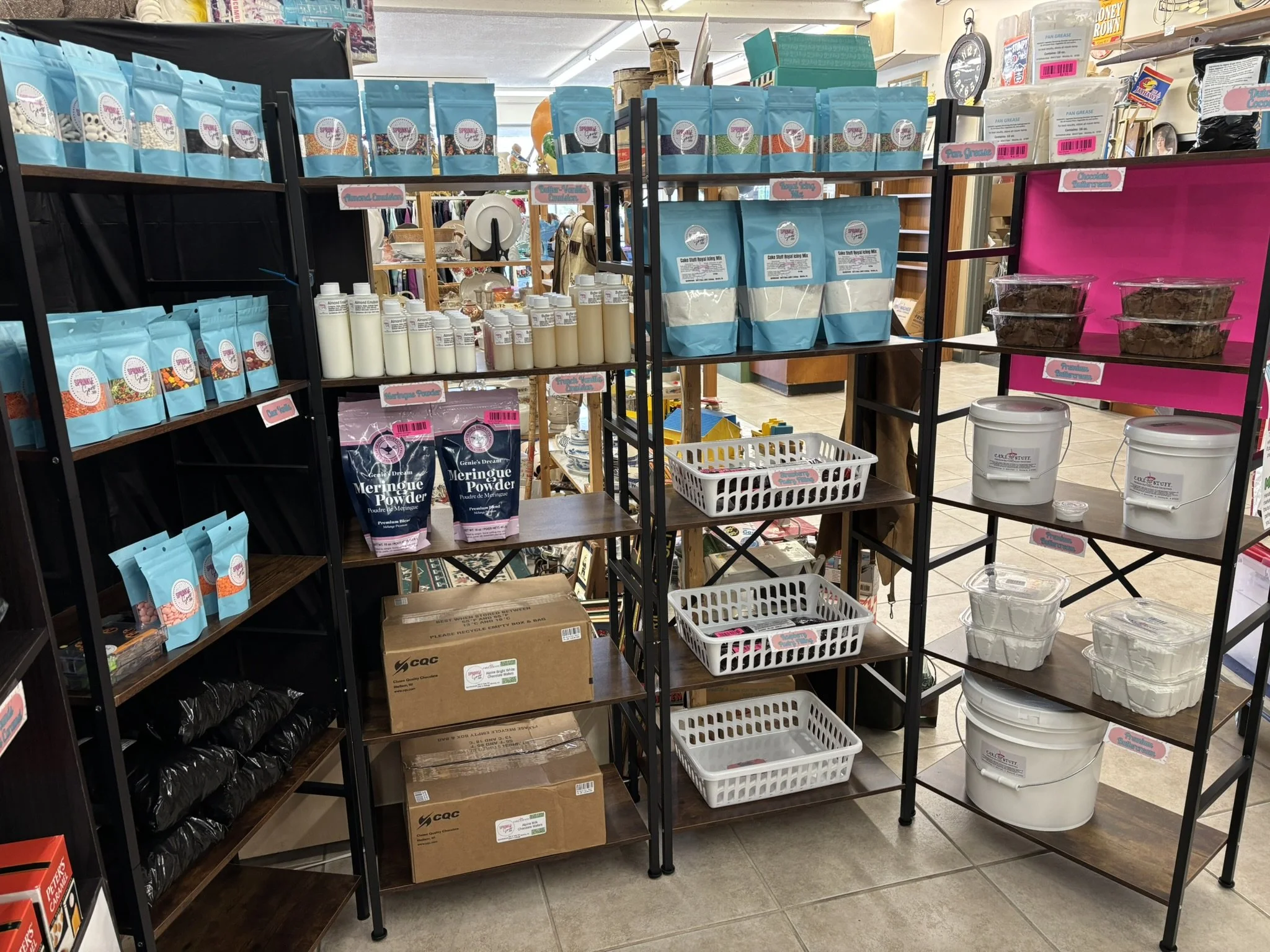 Shelves displaying various baking ingredients and supplies, including icing, powders, and containers in a store.
