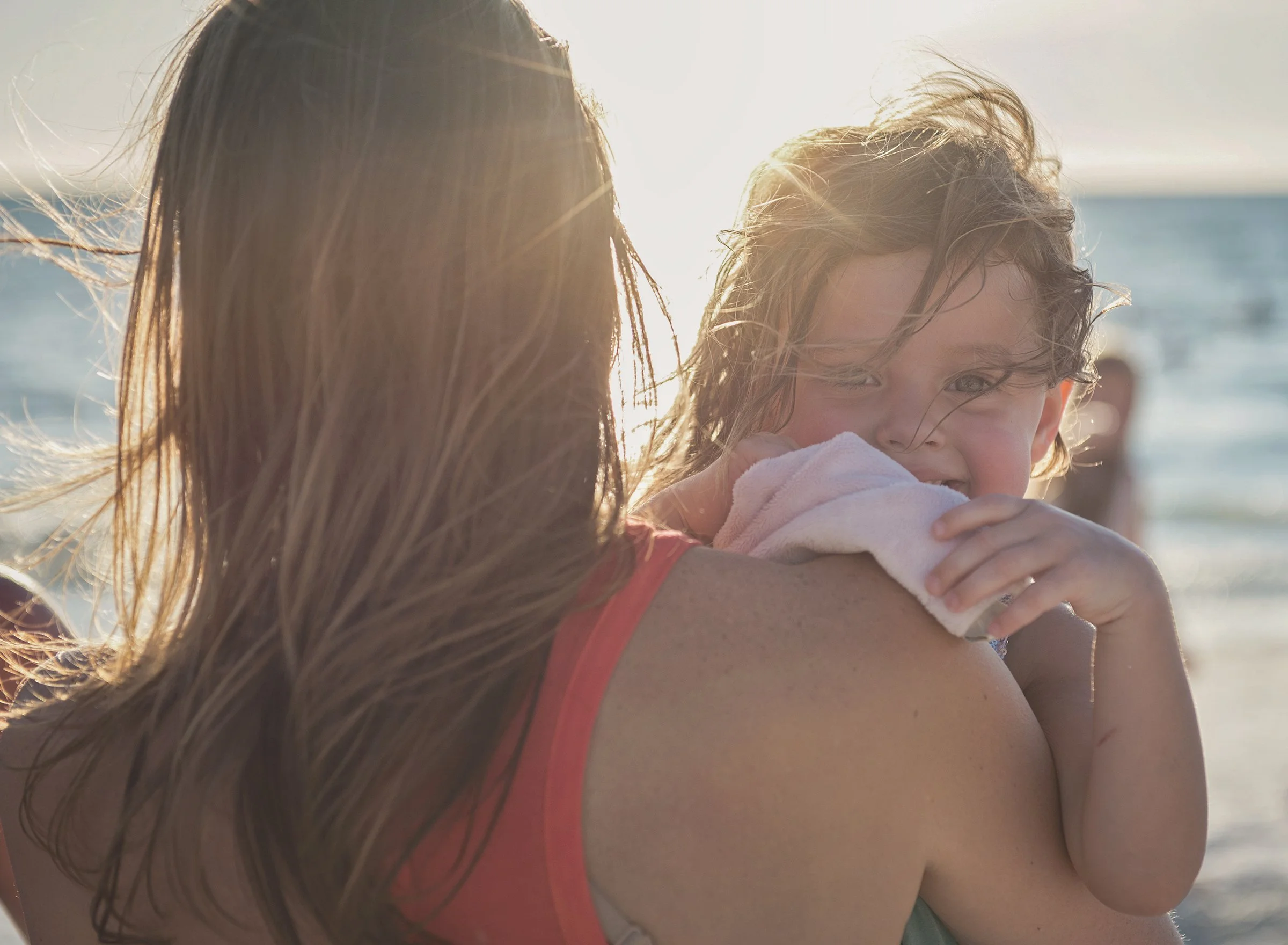 Young girl looking over woman's shoulder at sunset on St Pete Beach