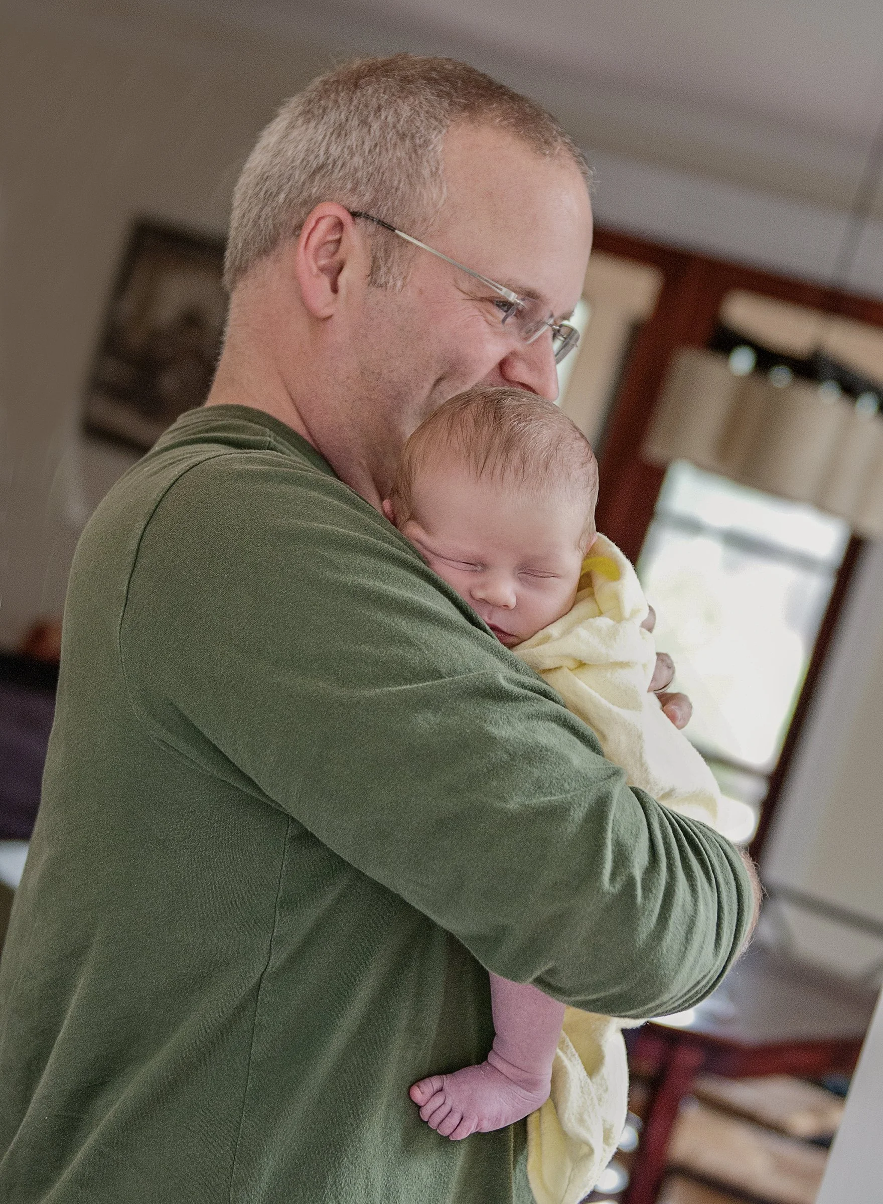 Man holding sleeping newborn baby