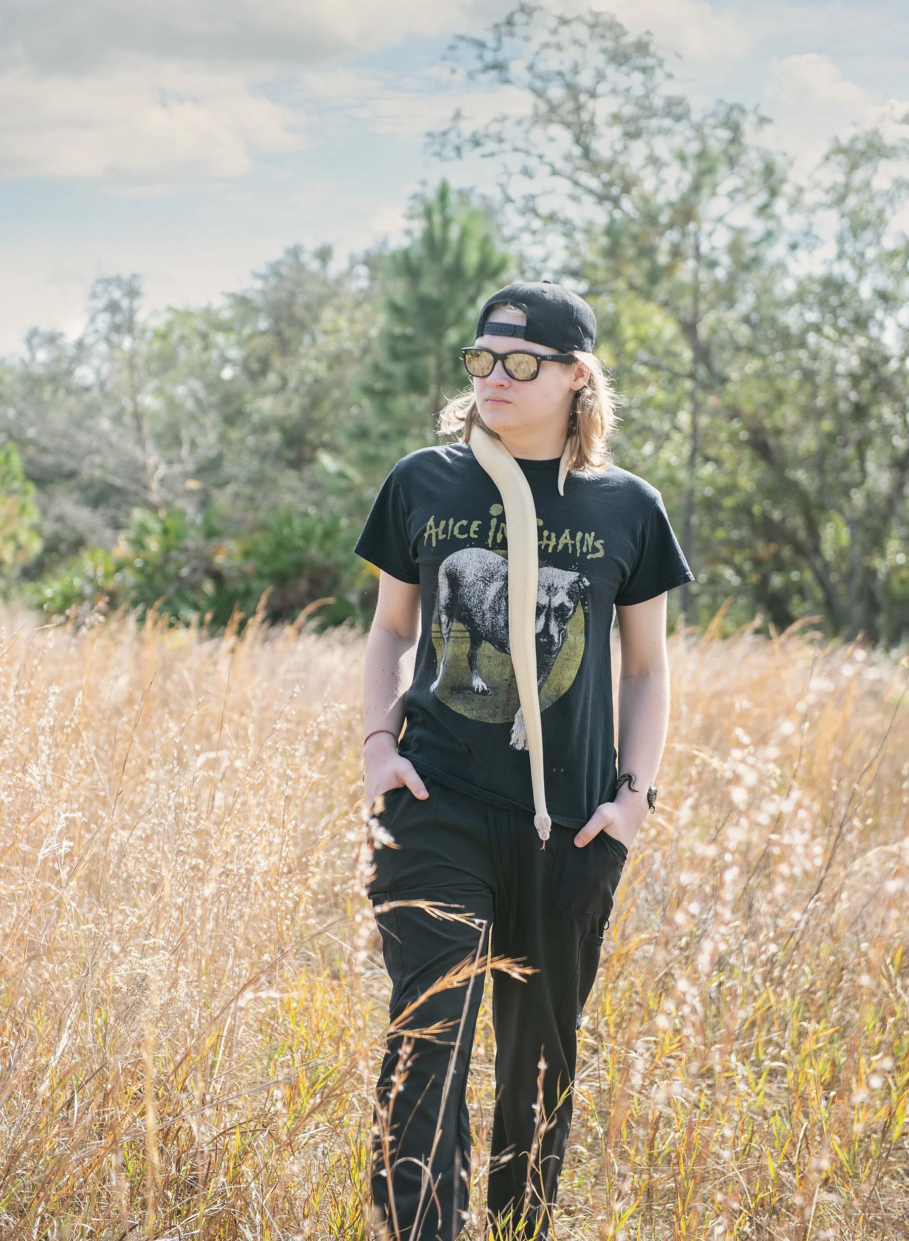 Teen boy walking in a field with a pet python in Odessa