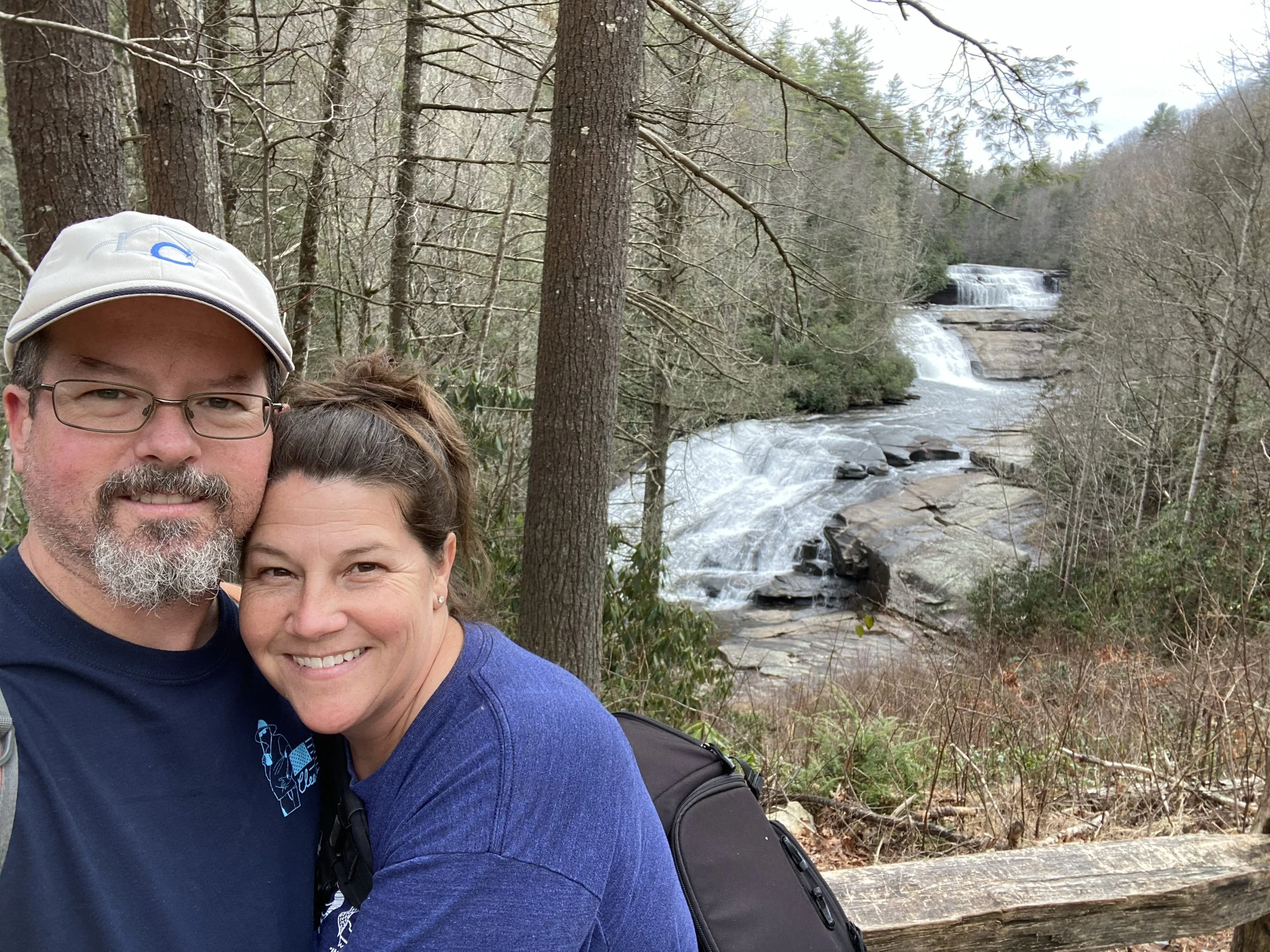 Man and woman hugging with a waterfall in the background on a family vacation