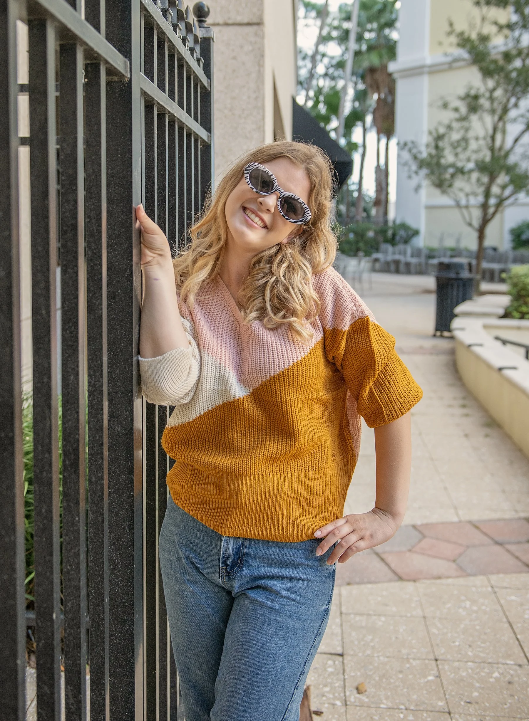 Teen girl wearing sunglasses holding on to an iron fence