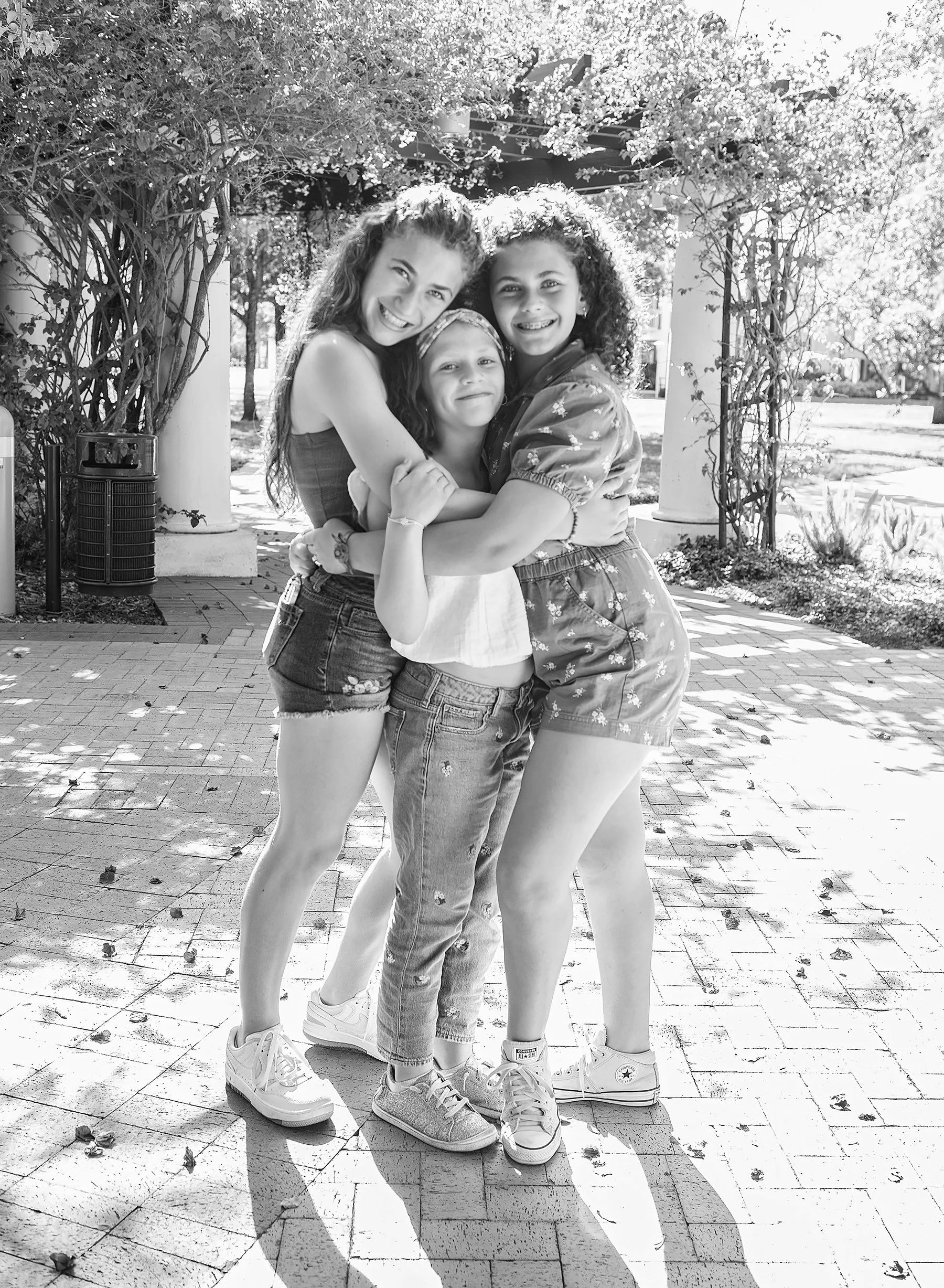 Two teenagers hugging with a younger girl between them