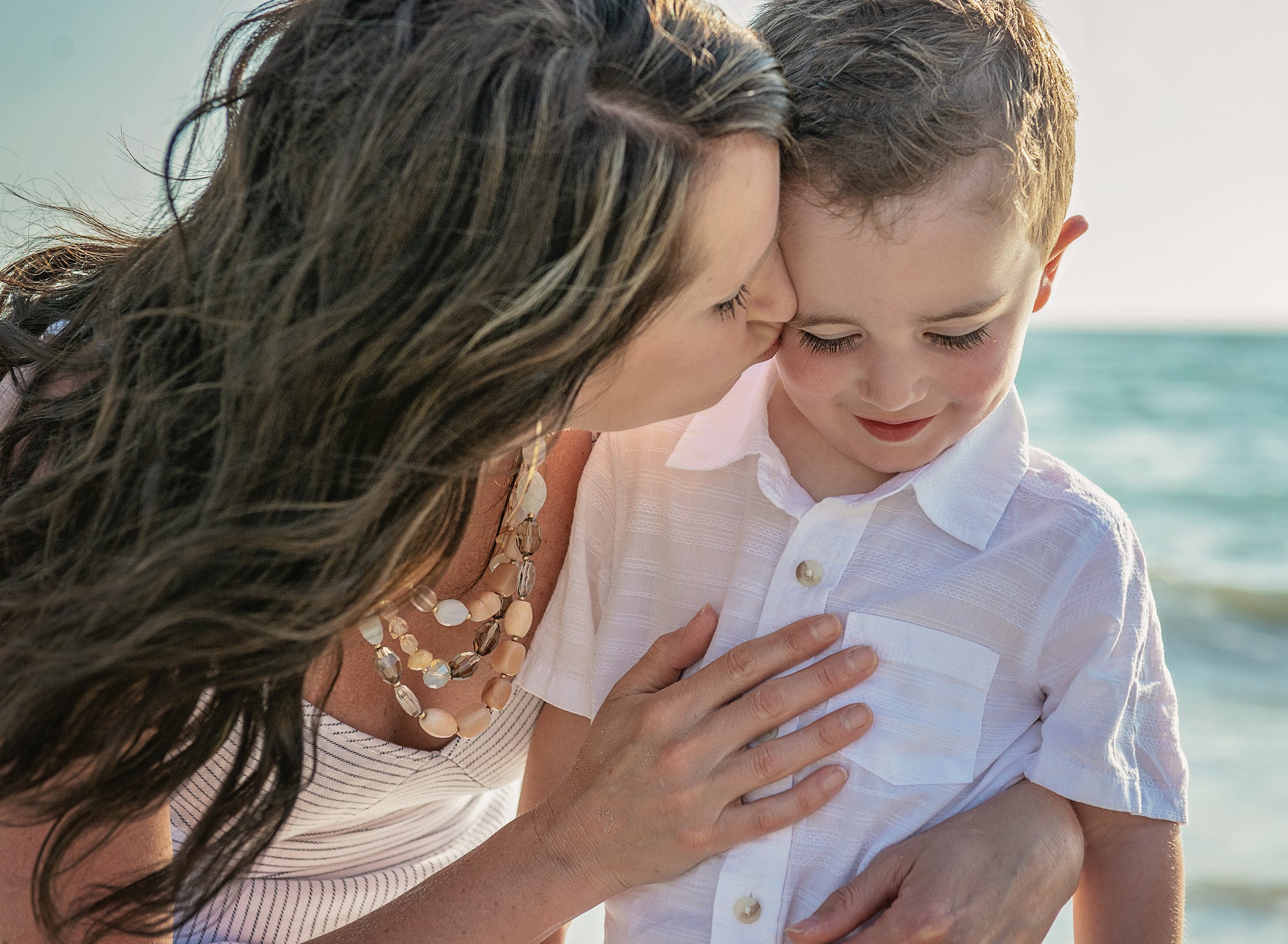 Woman kissing young boy on cheek at the beach in Clearwater