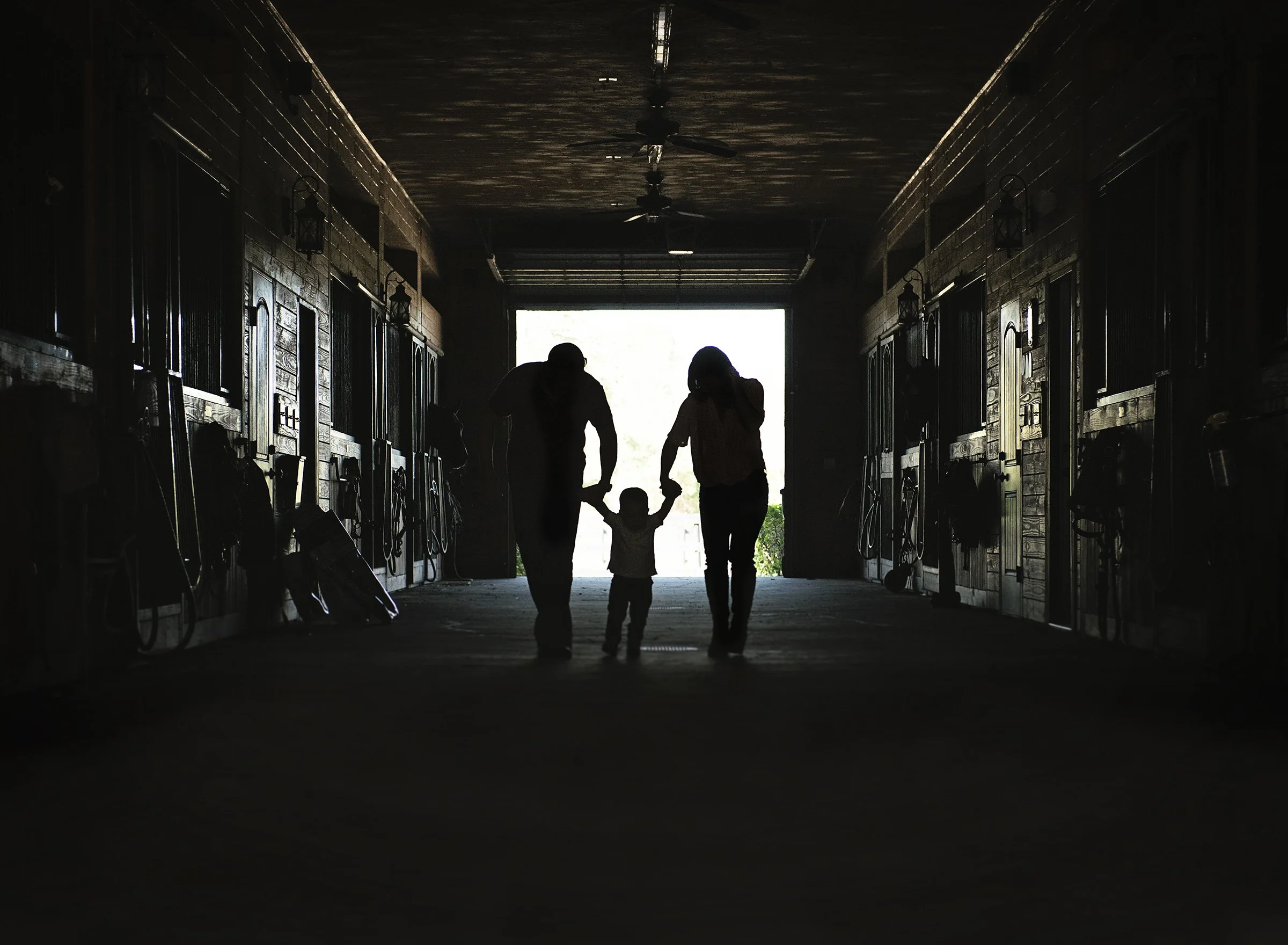 Couple holding toddler's hand in a barn