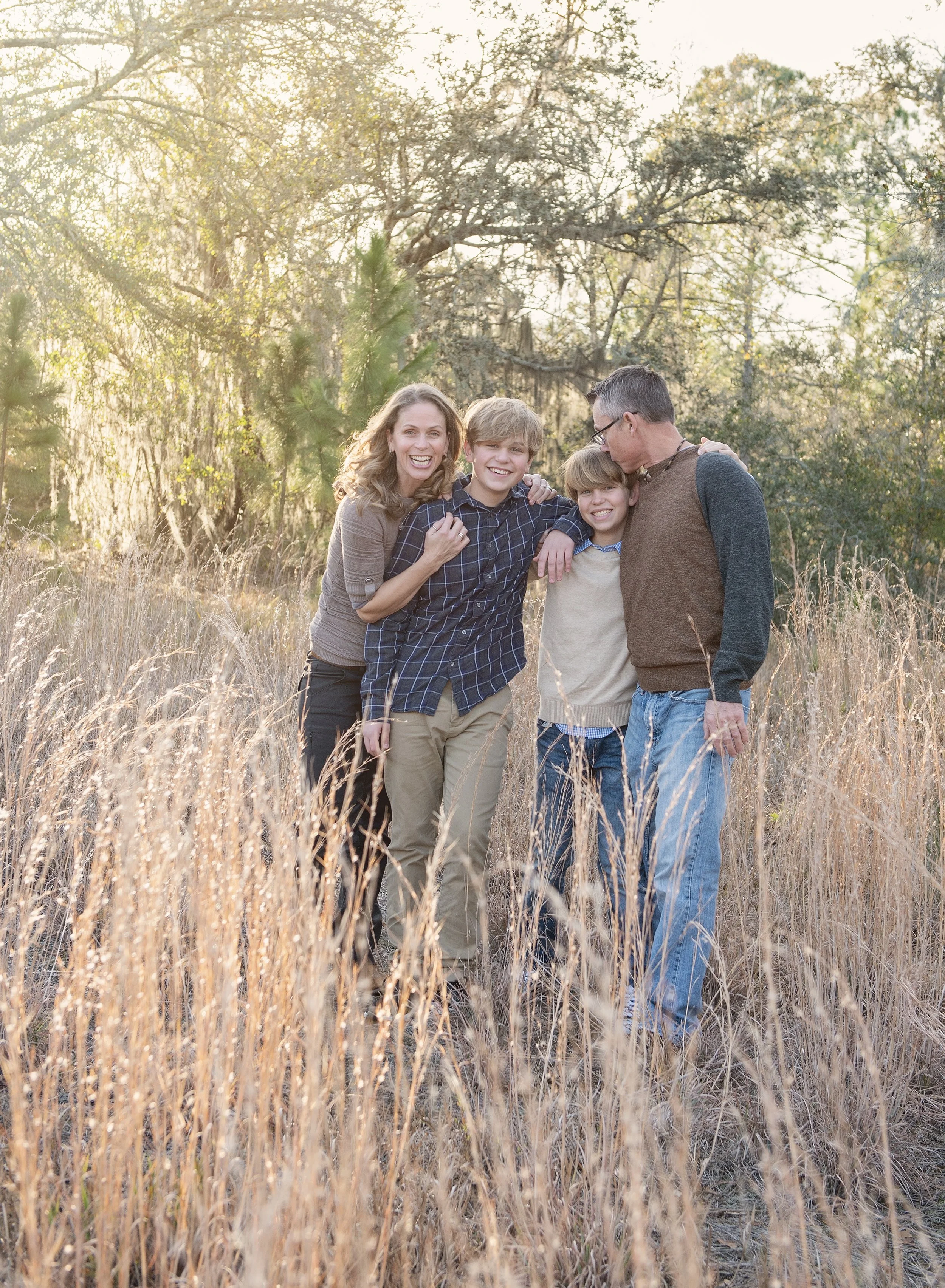 Family of four hugging in Odessa field at sunset
