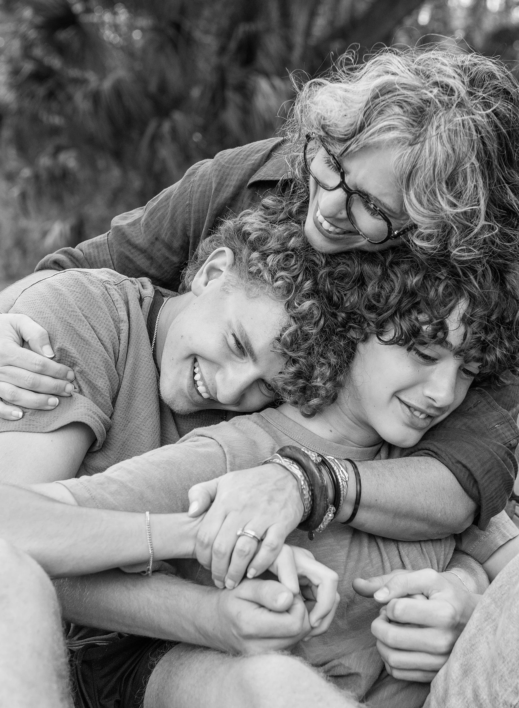 Woman hugging her two teenage boys and smiling