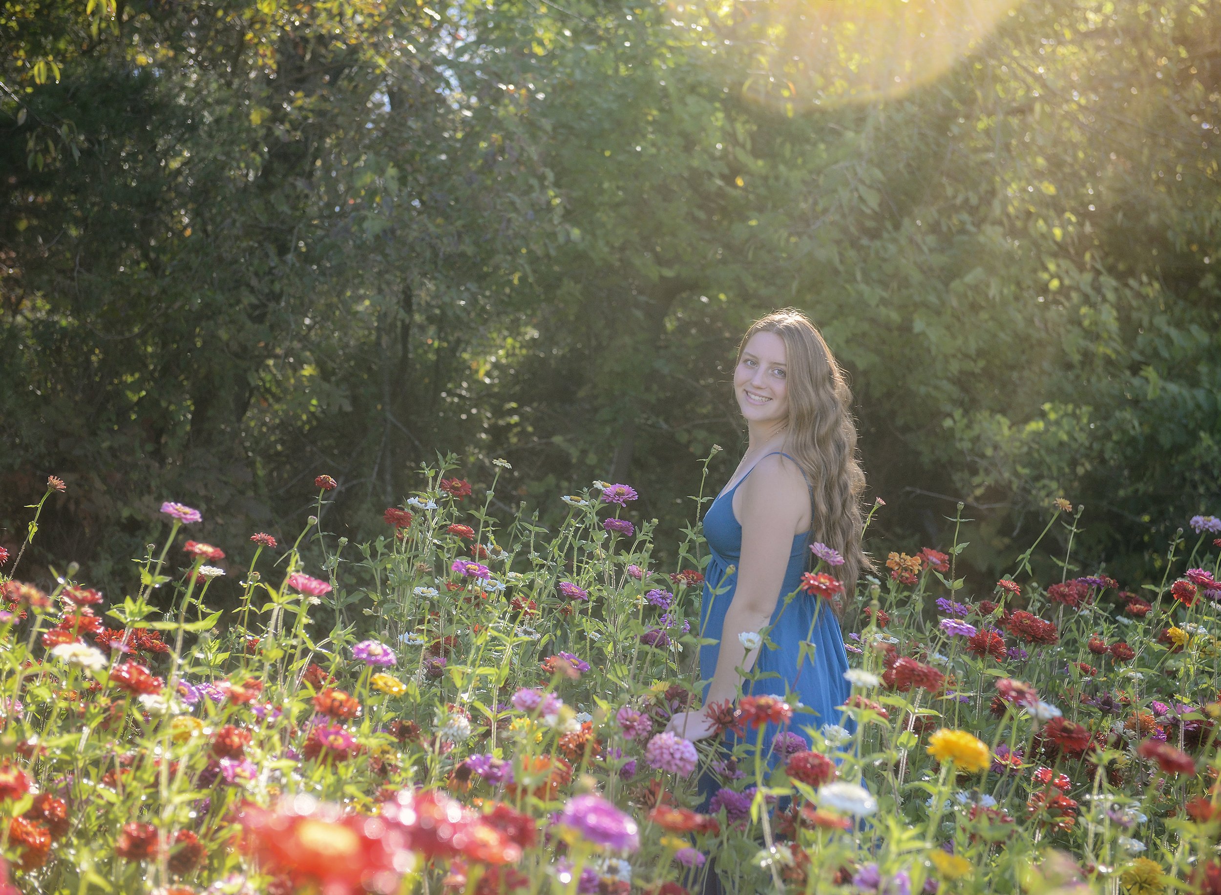 High school senior in a beautiful field of flowers, looking over her shoulder