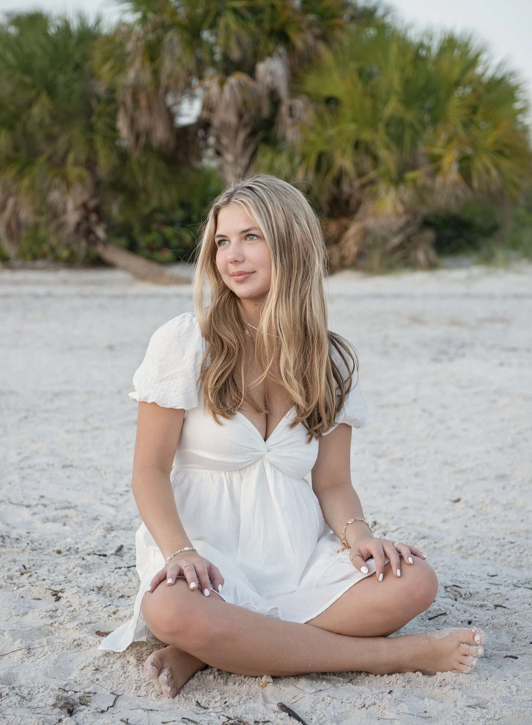 Teen girl in white dress sitting on the beach at Cypress Point Park in Tampa