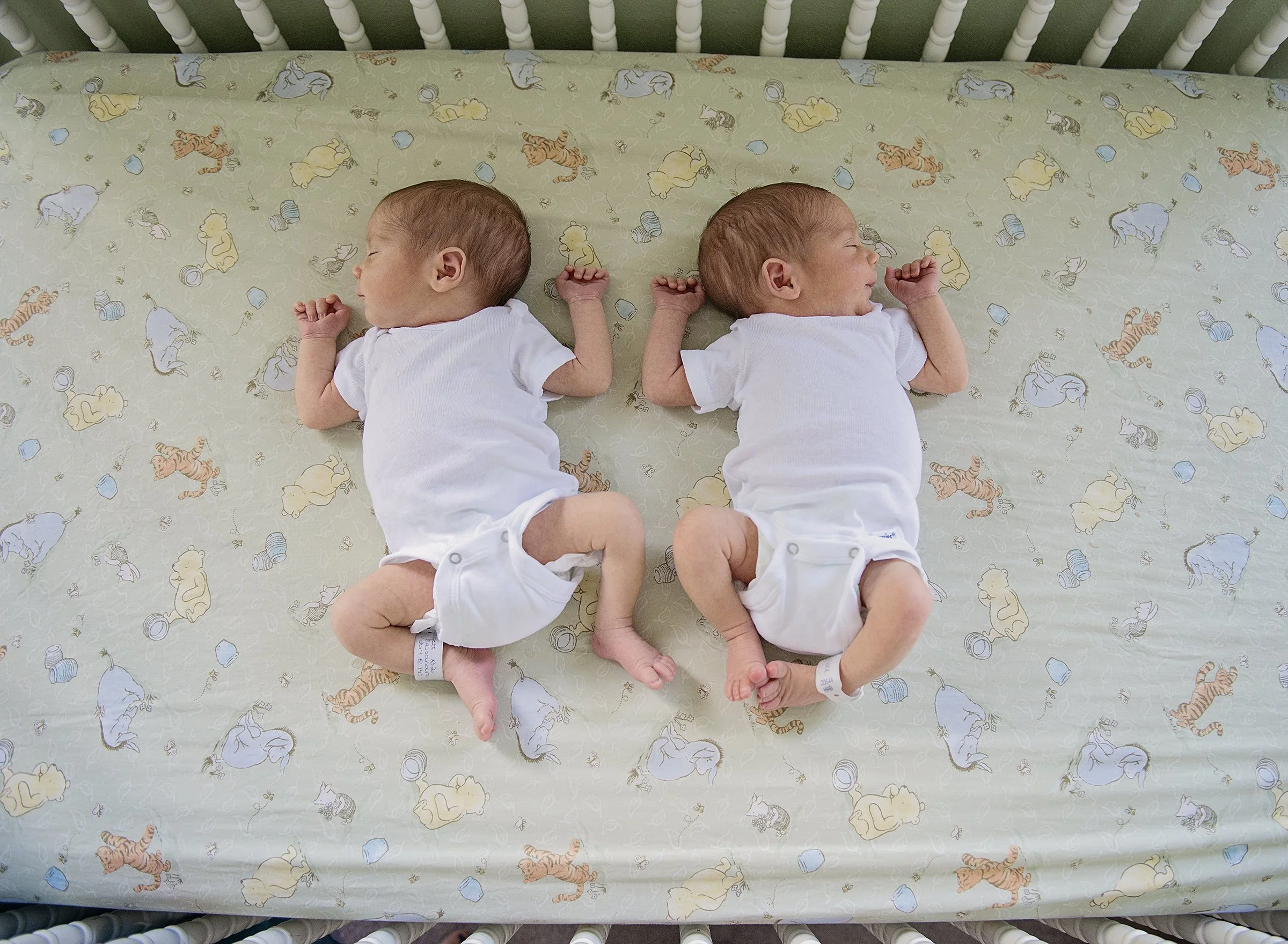 Newborn twin babies laying in a crib together