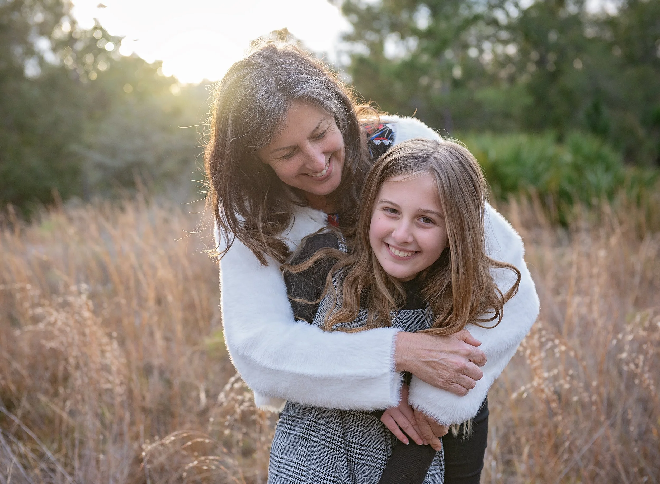 Woman and child hugging in a sunlit field in Odessa at sunset