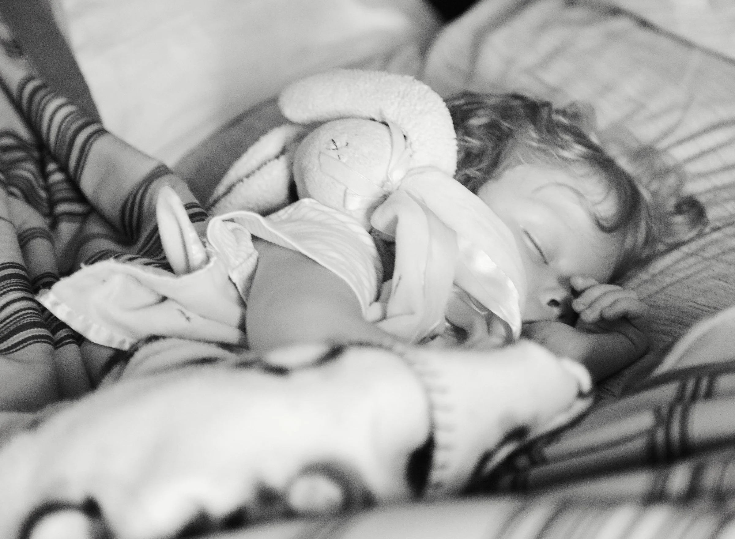 Toddler sucking her thumb and holding her stuffed bunny while sleeping
