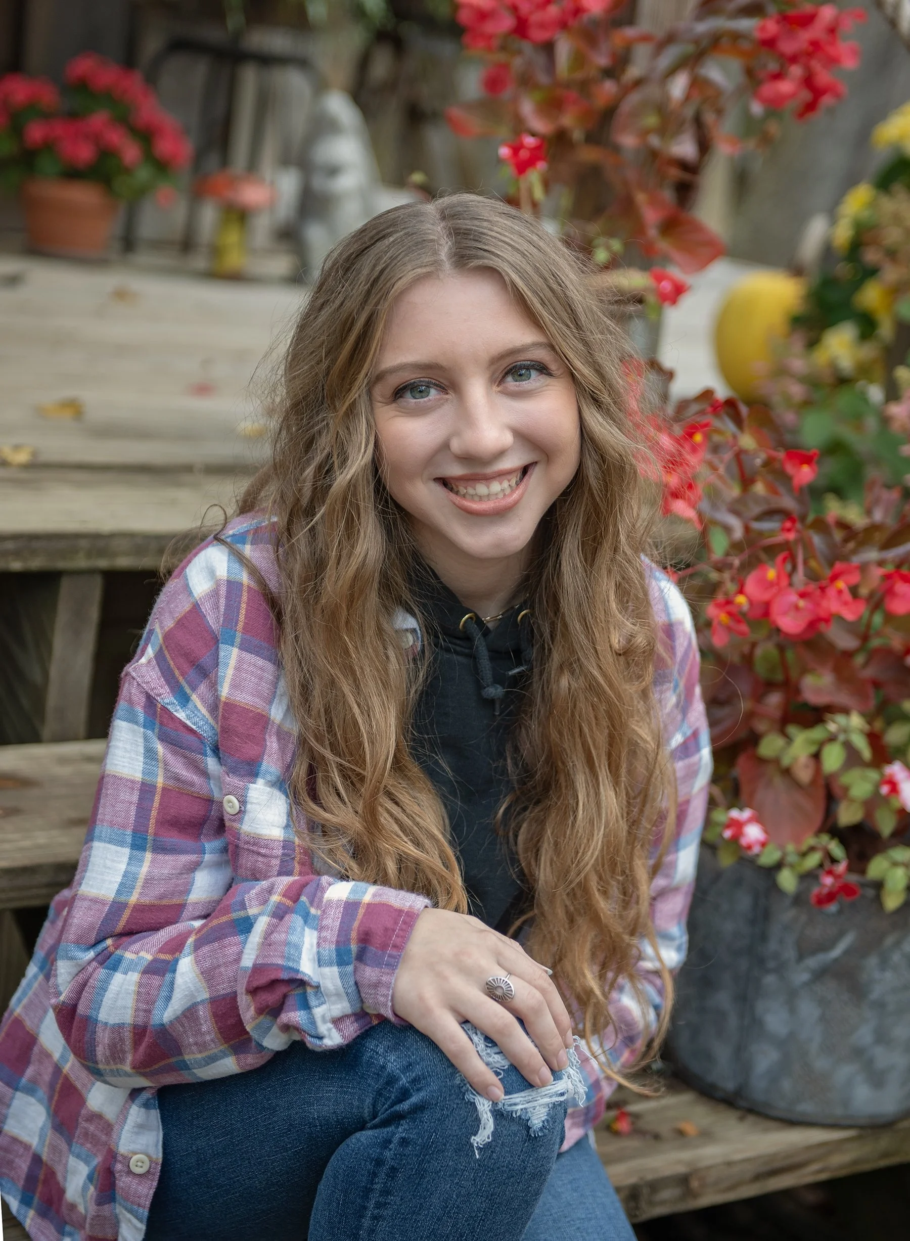 Teen girl sitting on wooden steps with flowers behind her