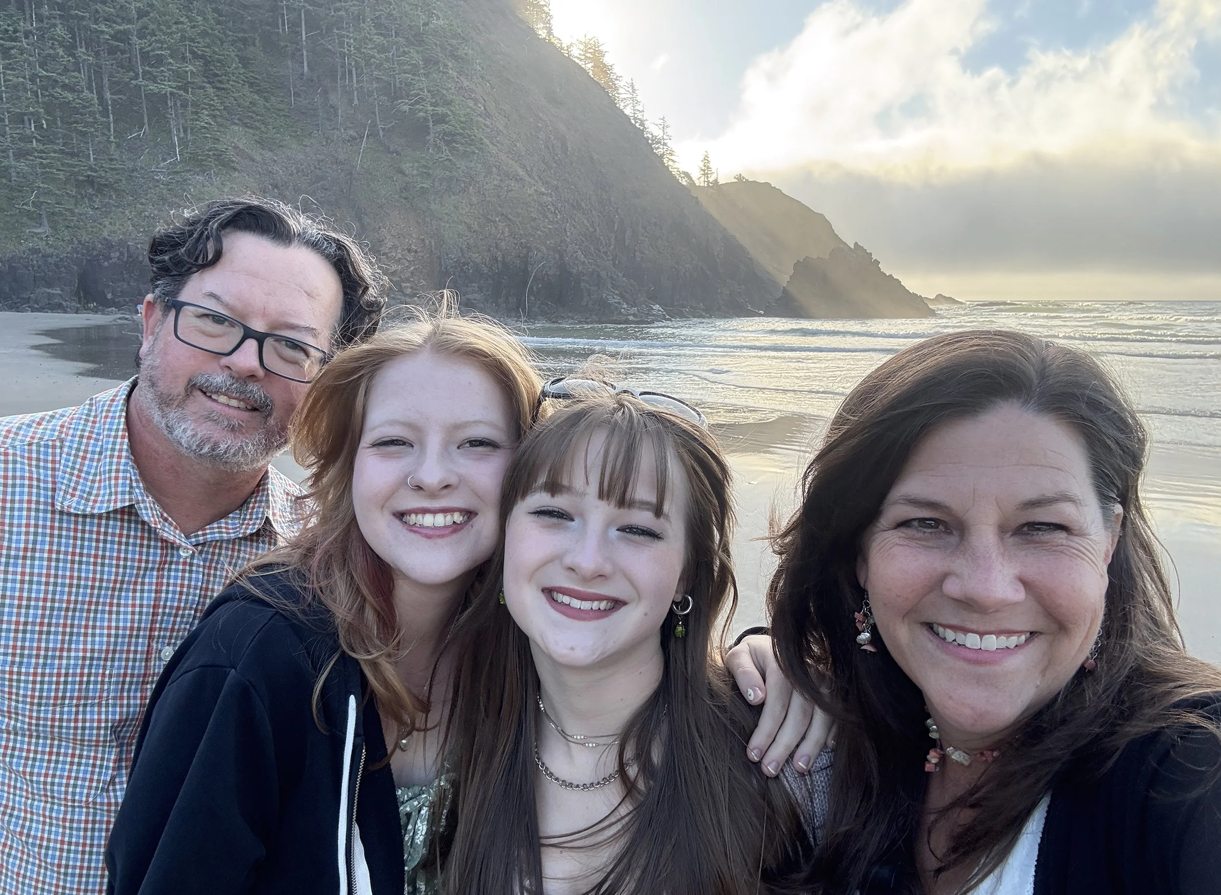 Family self portrait on a beach with sunset behind them