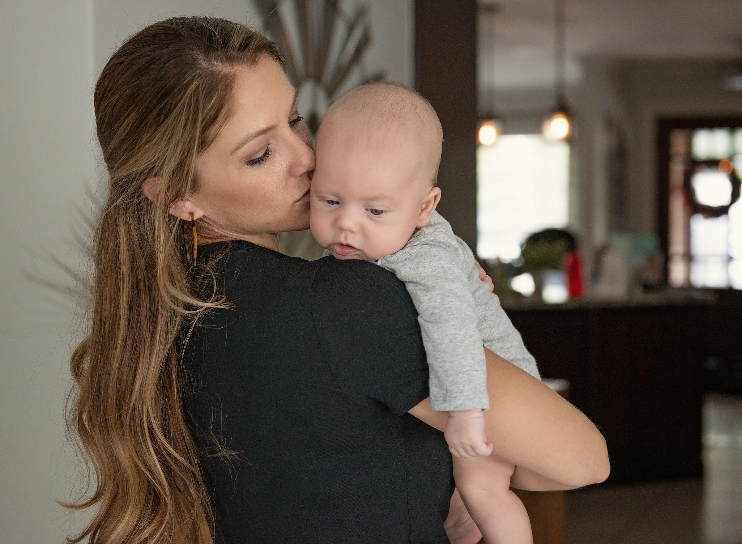 Woman kissing newborn baby's cheek