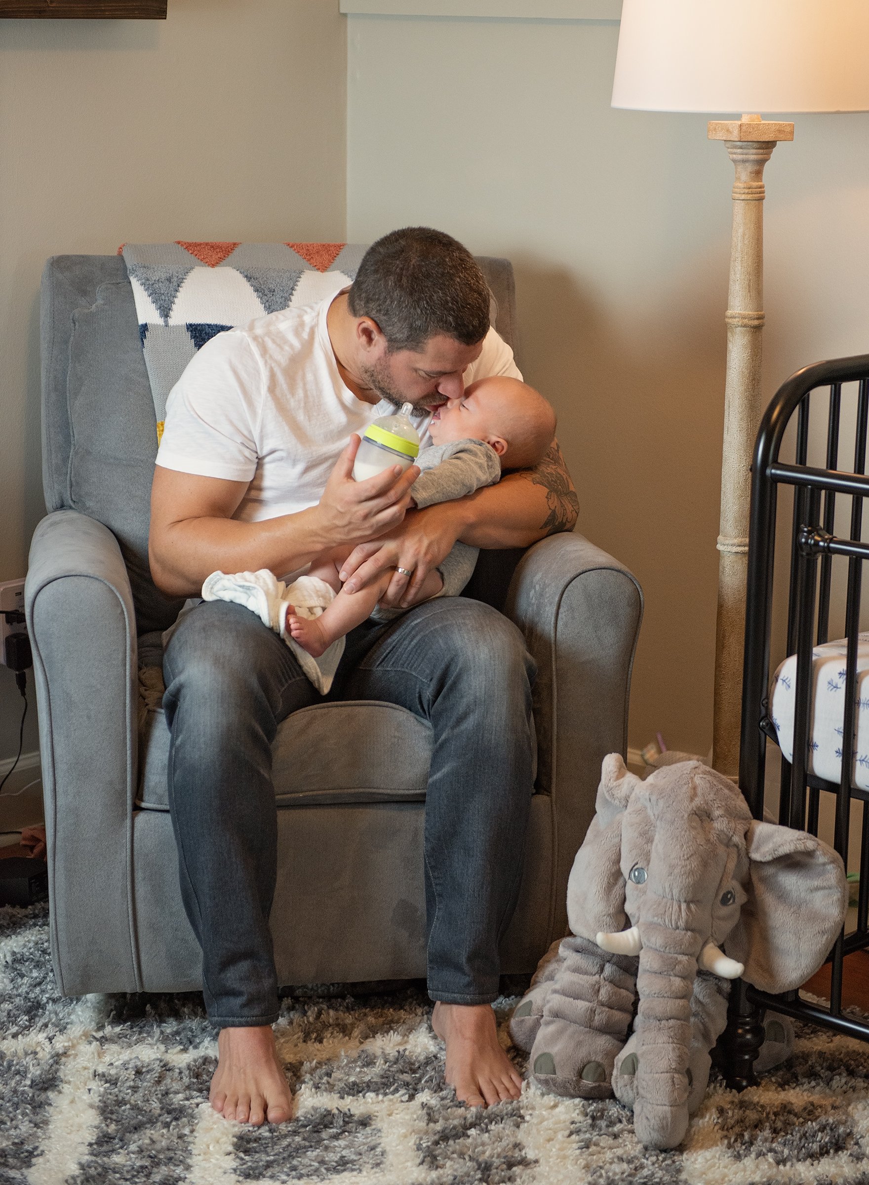Man sitting in a rocking chair holding a newborn baby