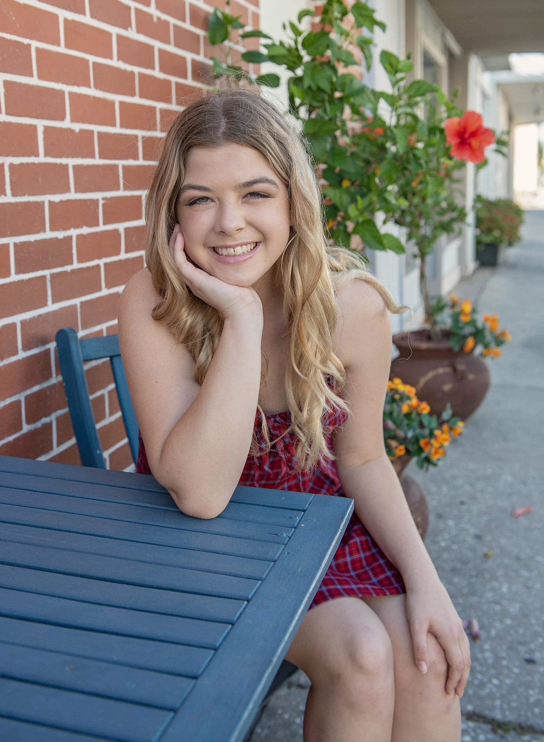Teen girl sitting at a table in Clearwater with flowers behind her