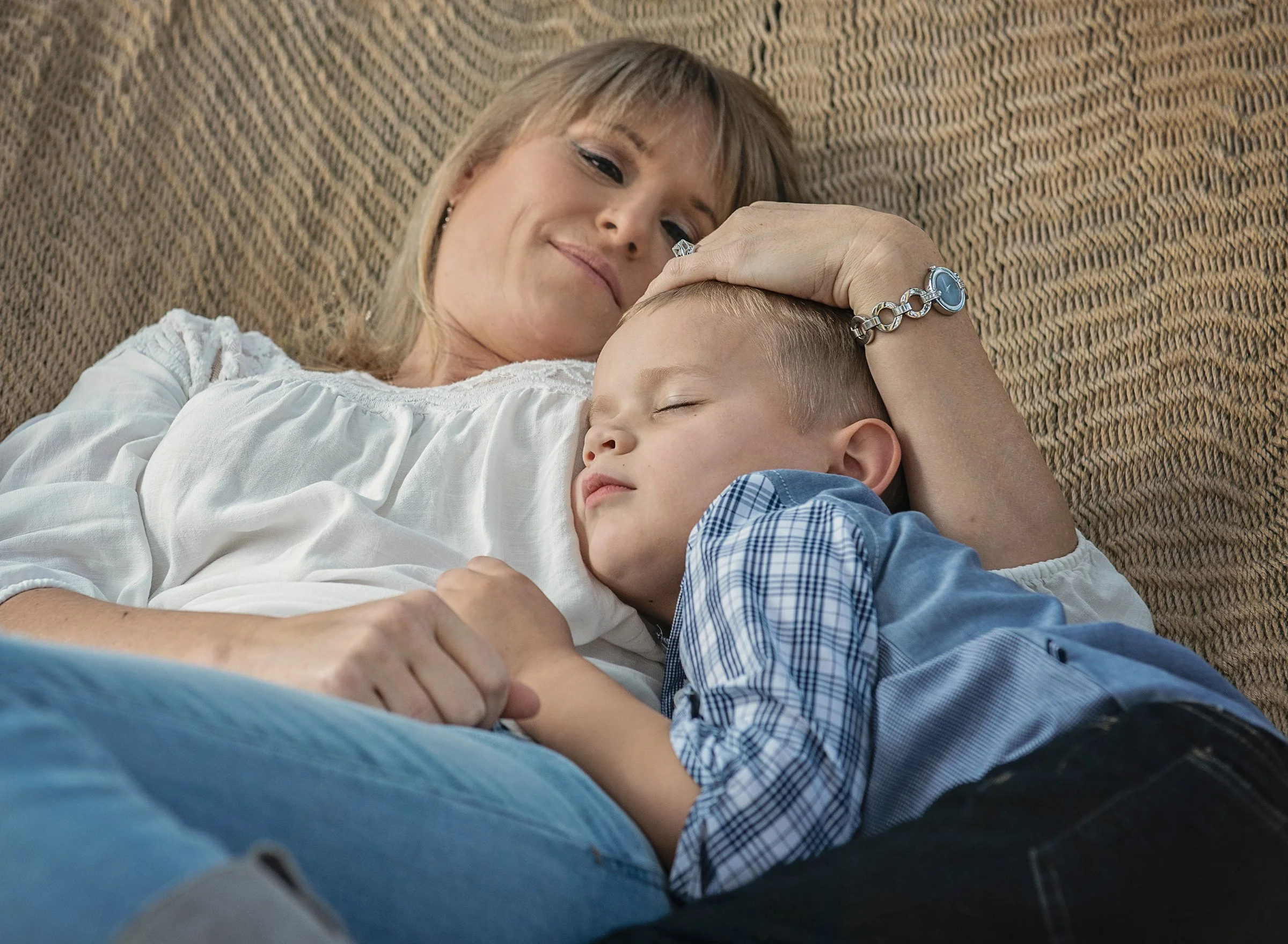 Woman snuggling young son in hammock at home