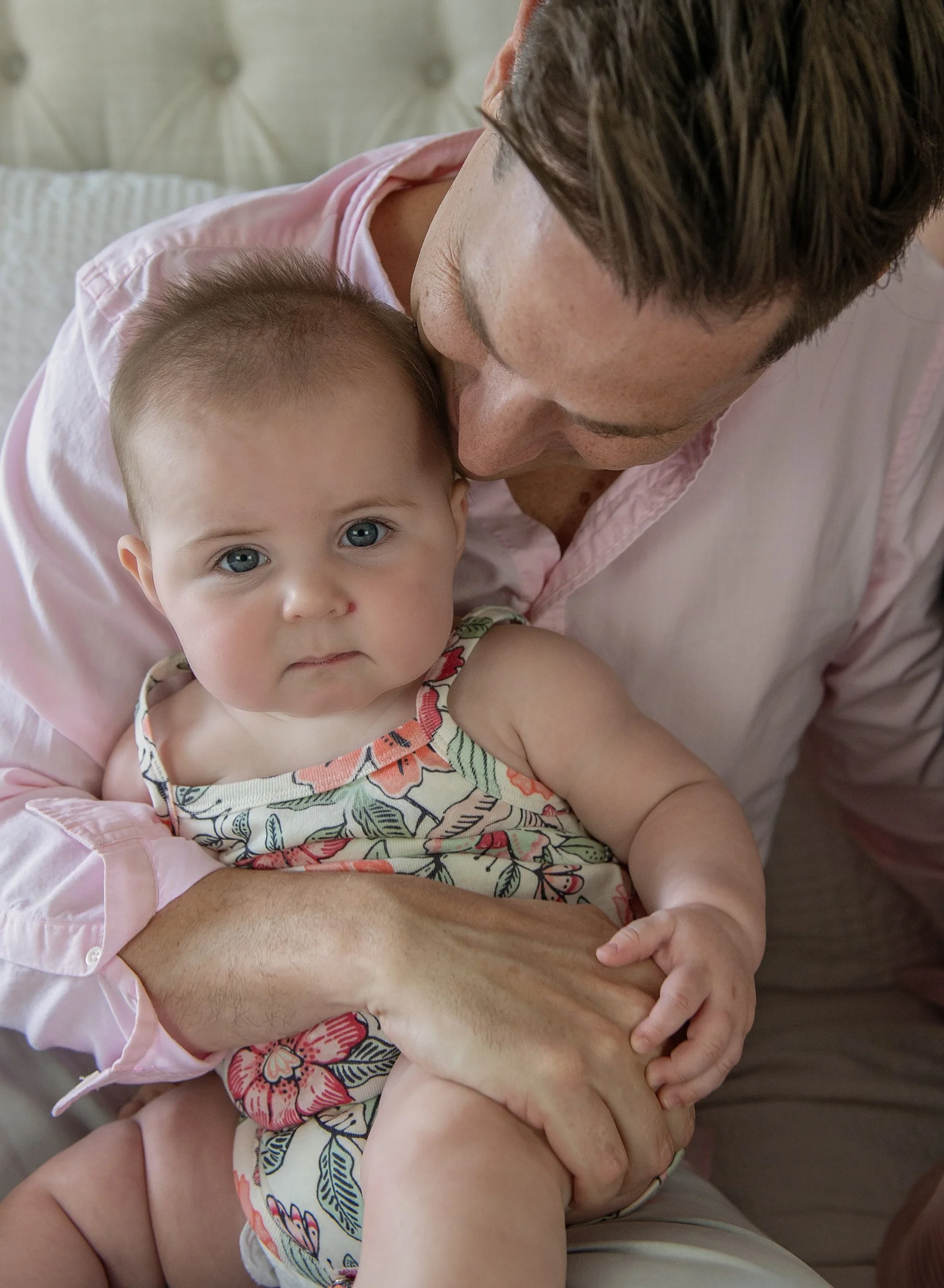 Infant sitting on man's lap on a bed