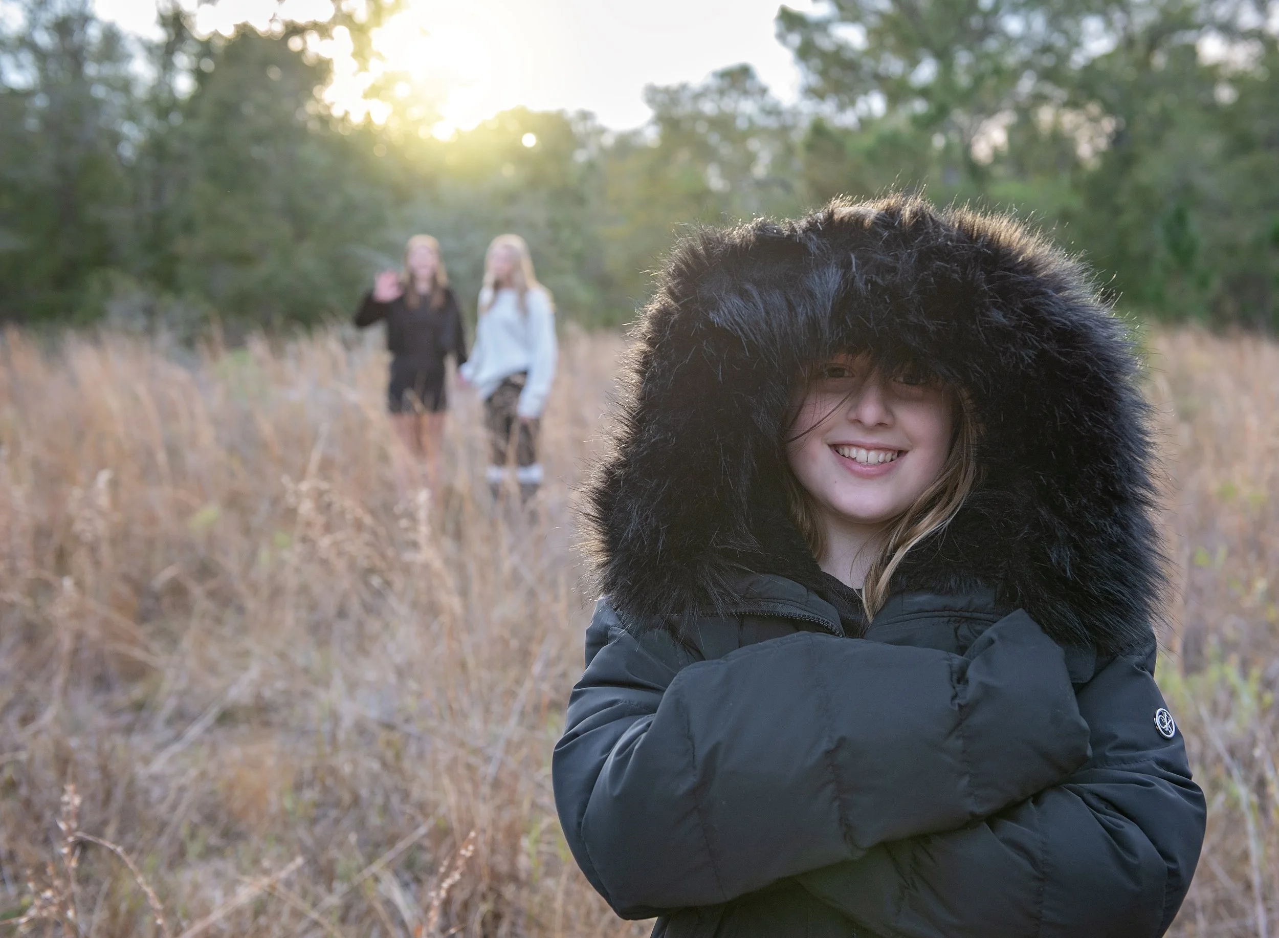 Young girl in a puffer jacket at sunset with two girls in the background