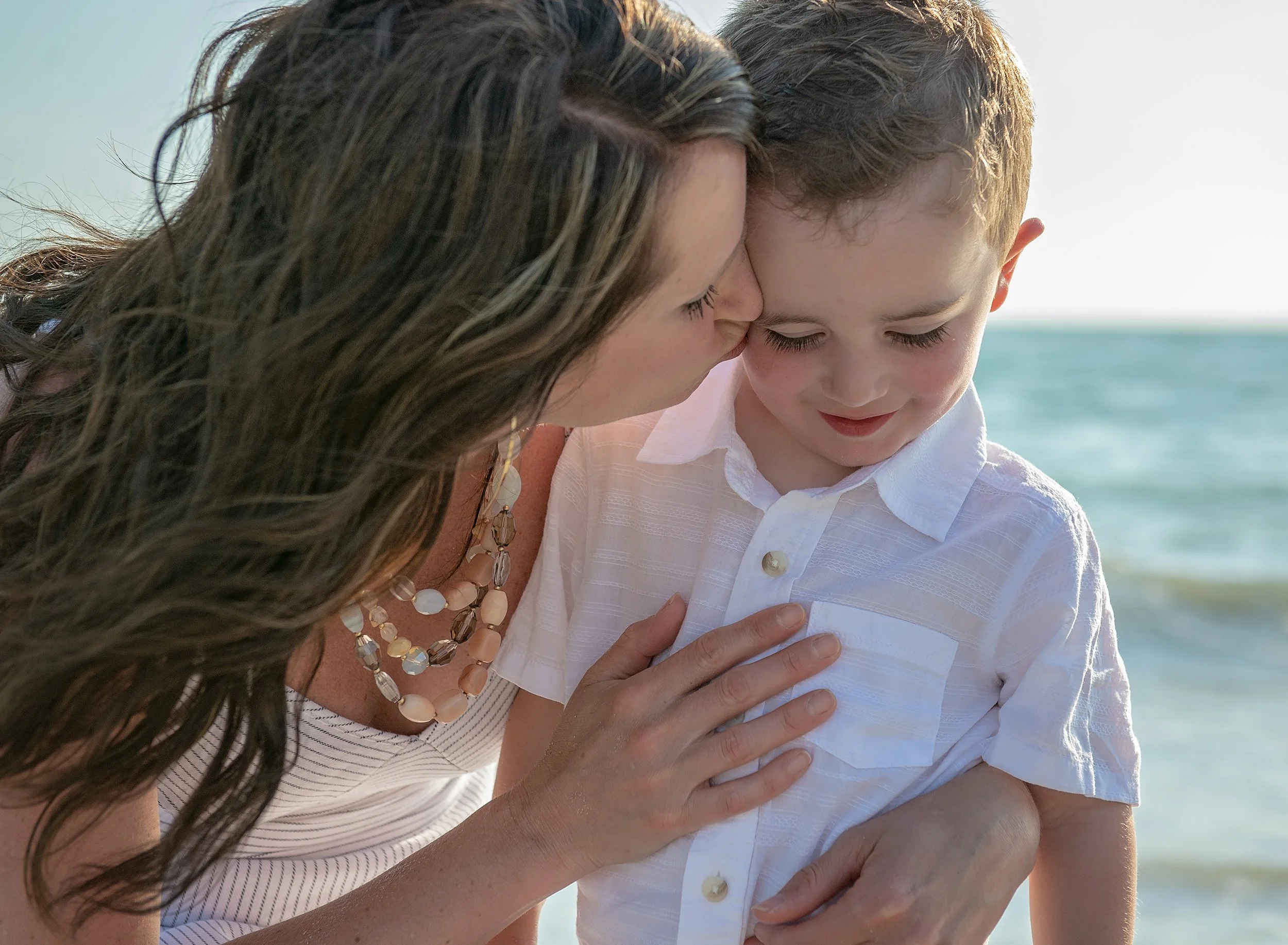 Candid family moment of a mother comforting her young son during a beach photo session in Tampa, FL.