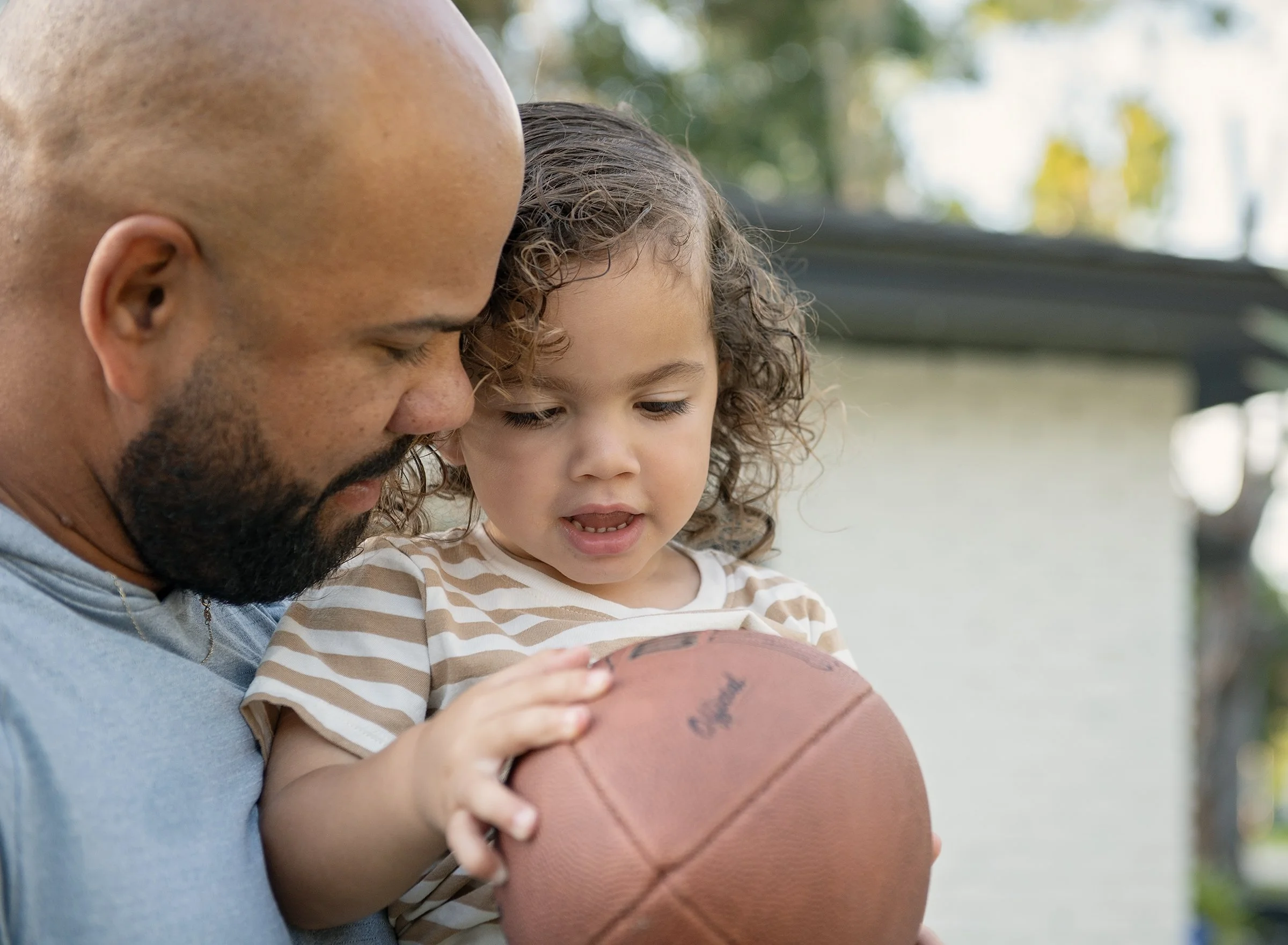 Man holding toddler and football at home
