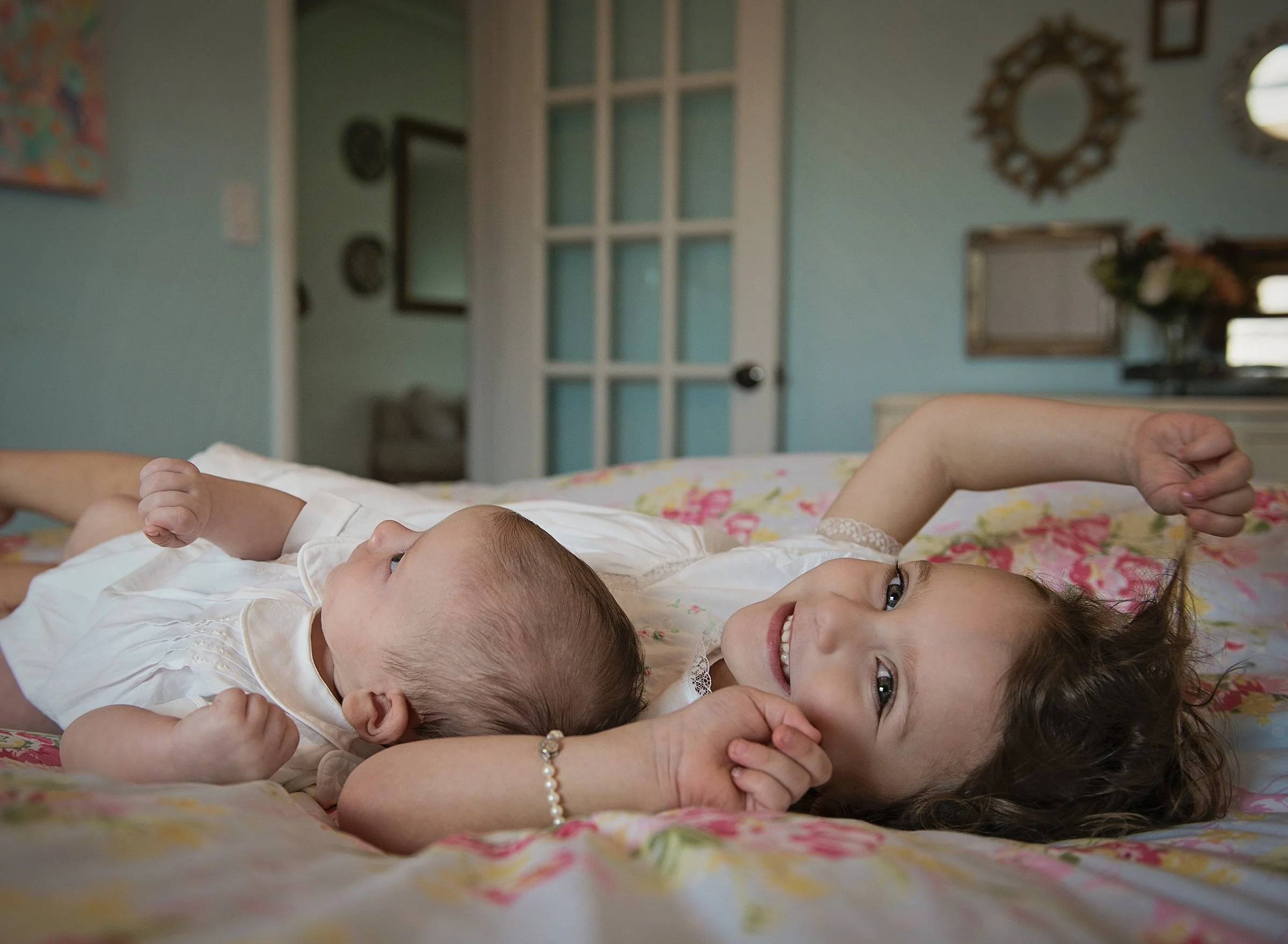 Young girl and newborn baby laying on a bed