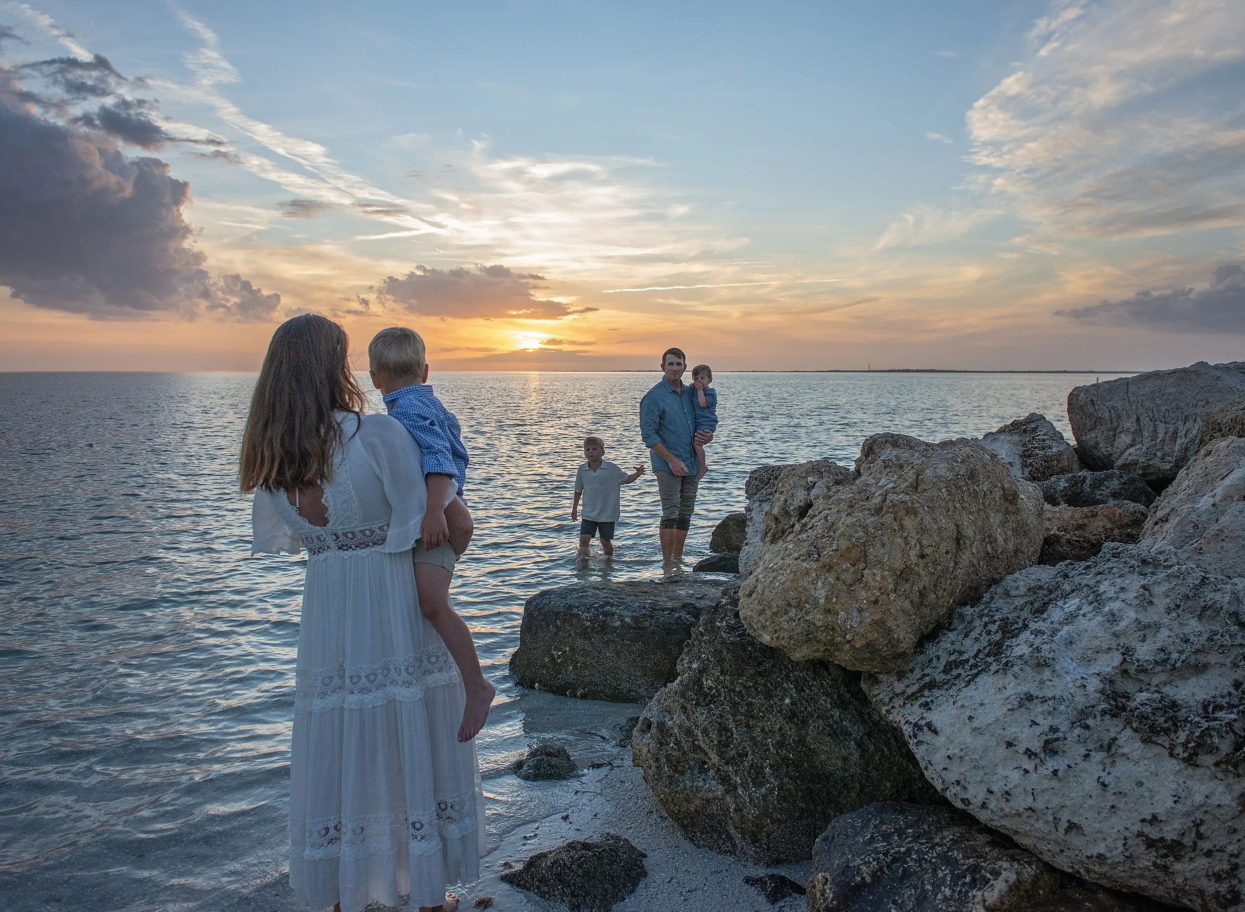 Family of five walking on the shoreline on a beach at sunset