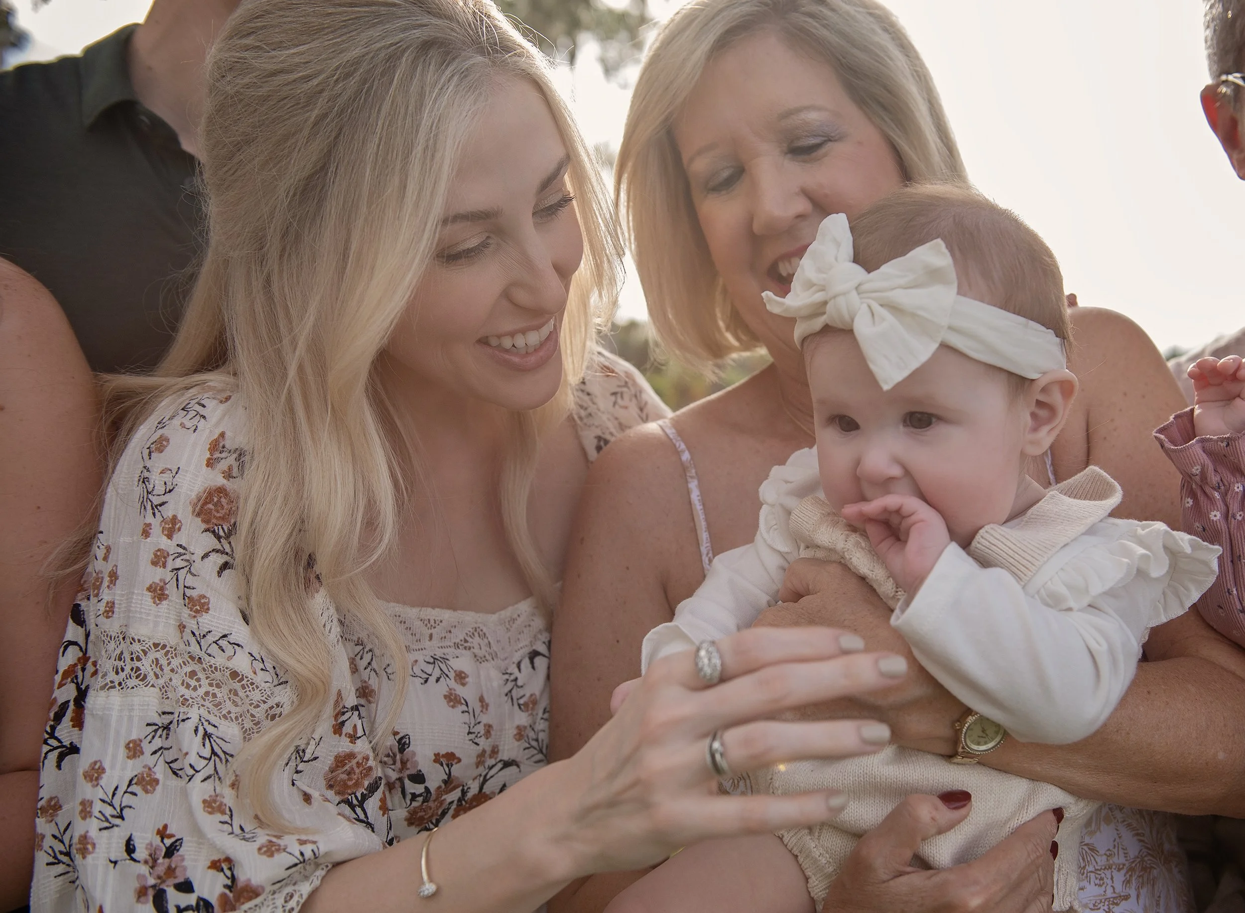 Two women holding baby and smiling at her