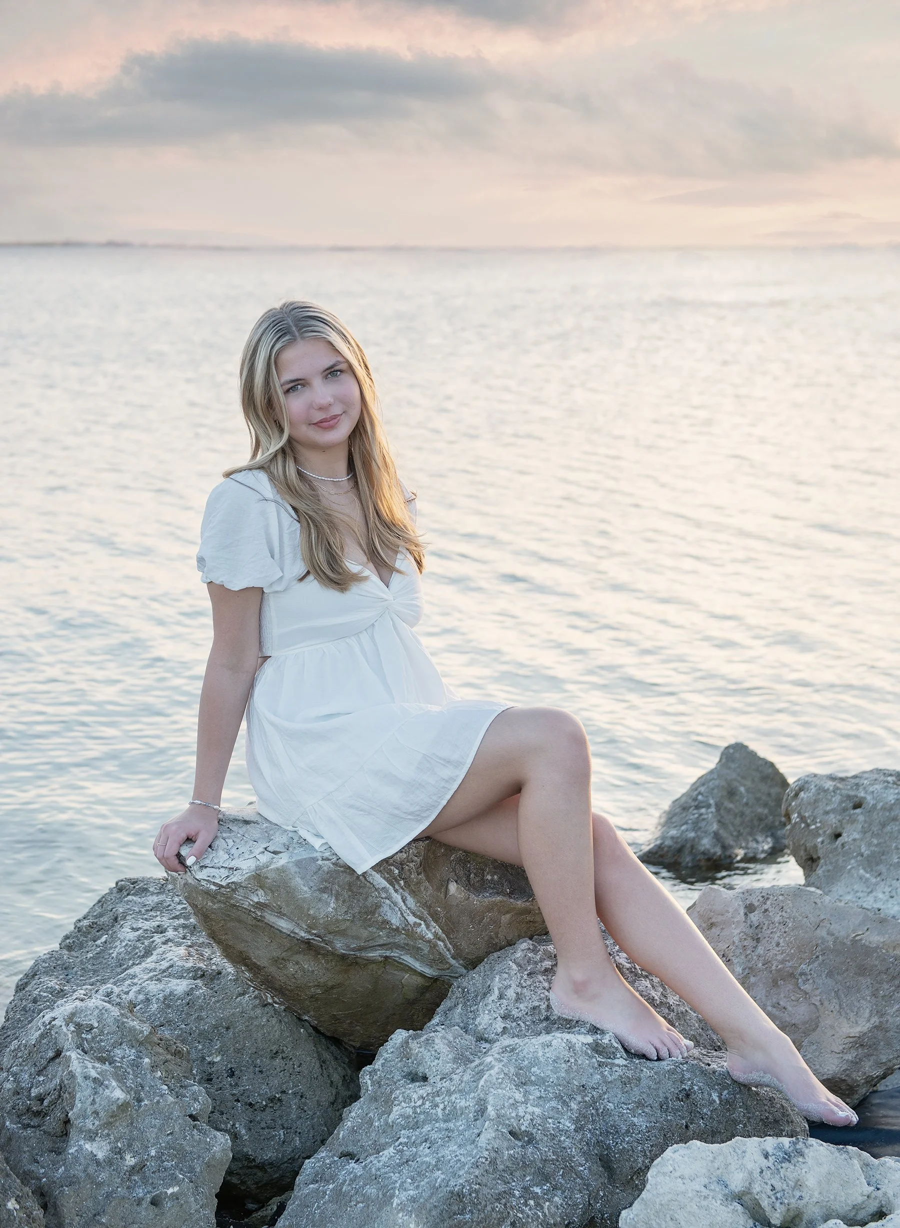Teen girl sitting on the rocks at Cypress Point Park in Tampa at sunset