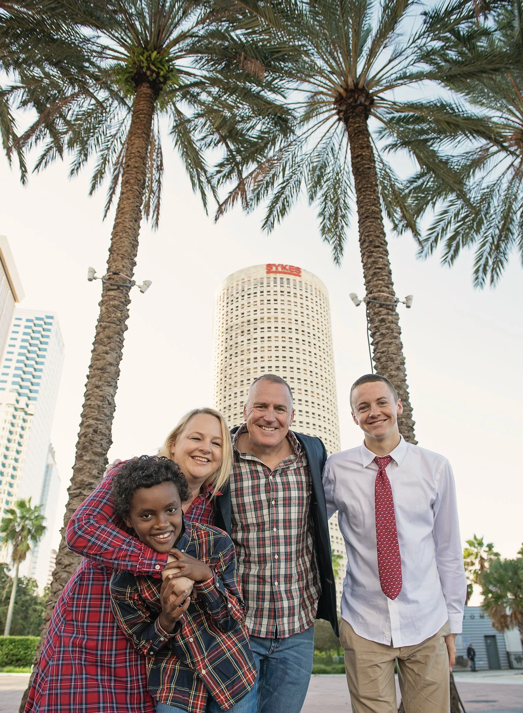 Family of four in downtown Tampa with palm trees behind them